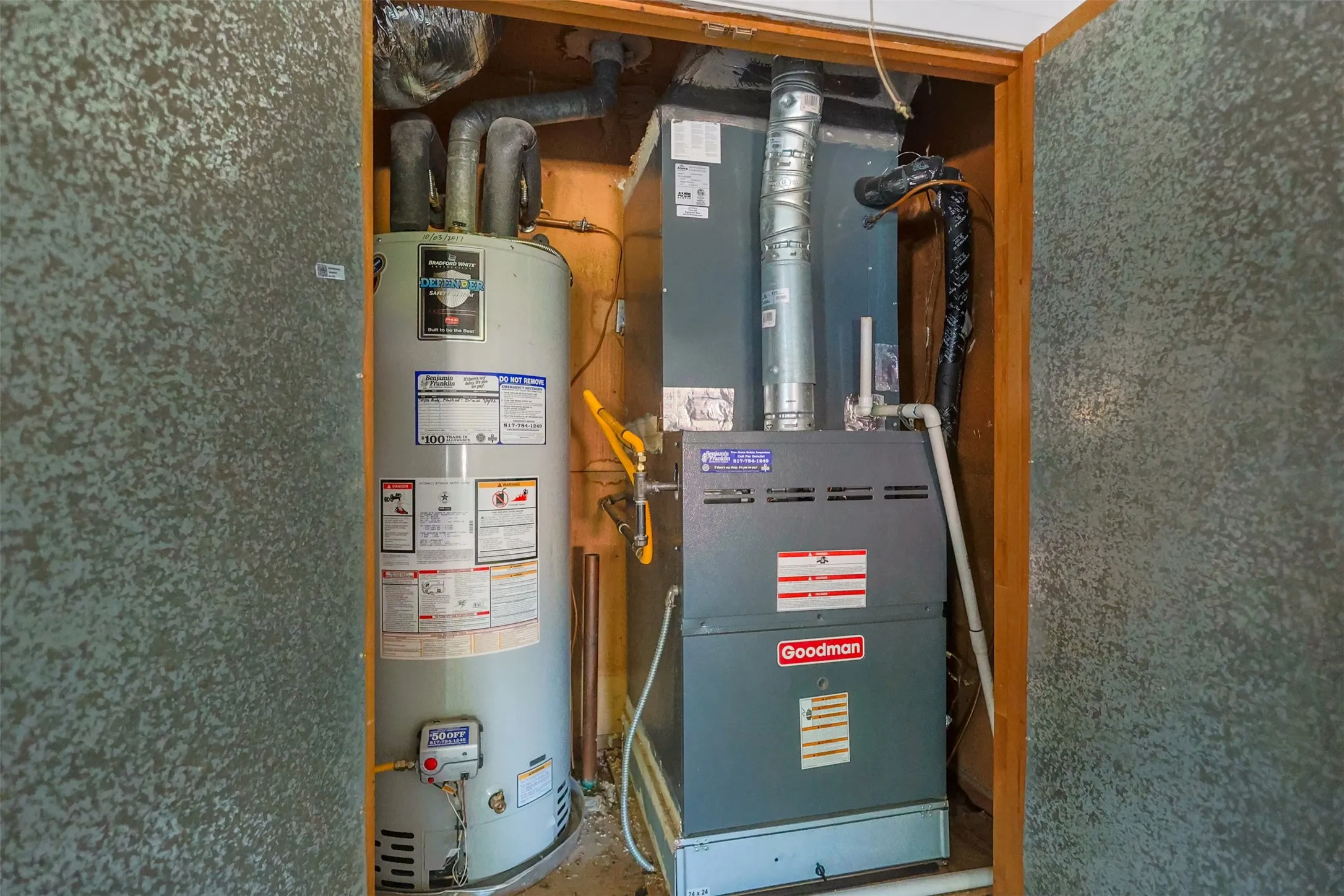 Utility closet featuring a water heater and furnace with exposed ductwork and copper piping