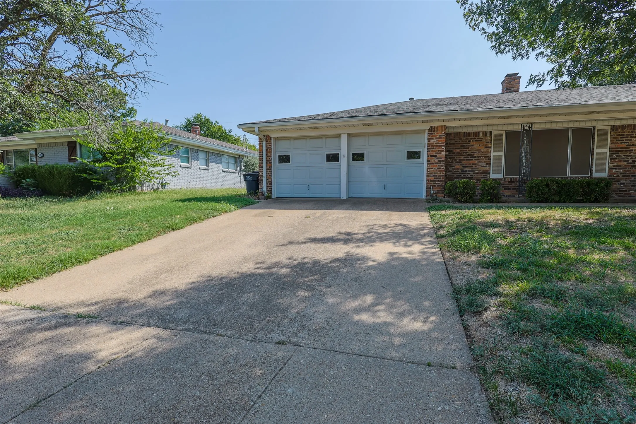 Brick exterior with white shutters and a two-car garage