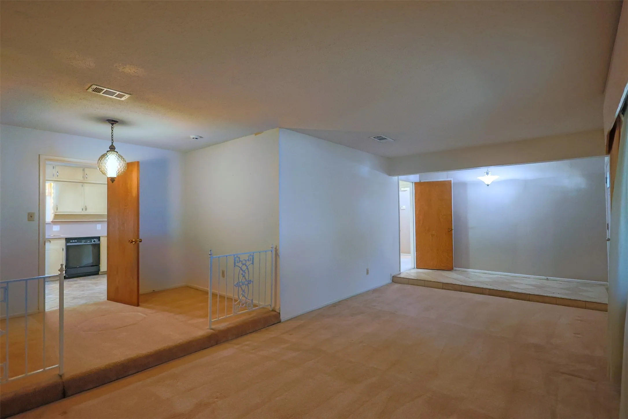 Carpeted living area featuring a raised platform, wood doors, and a decorative pendant light fixture