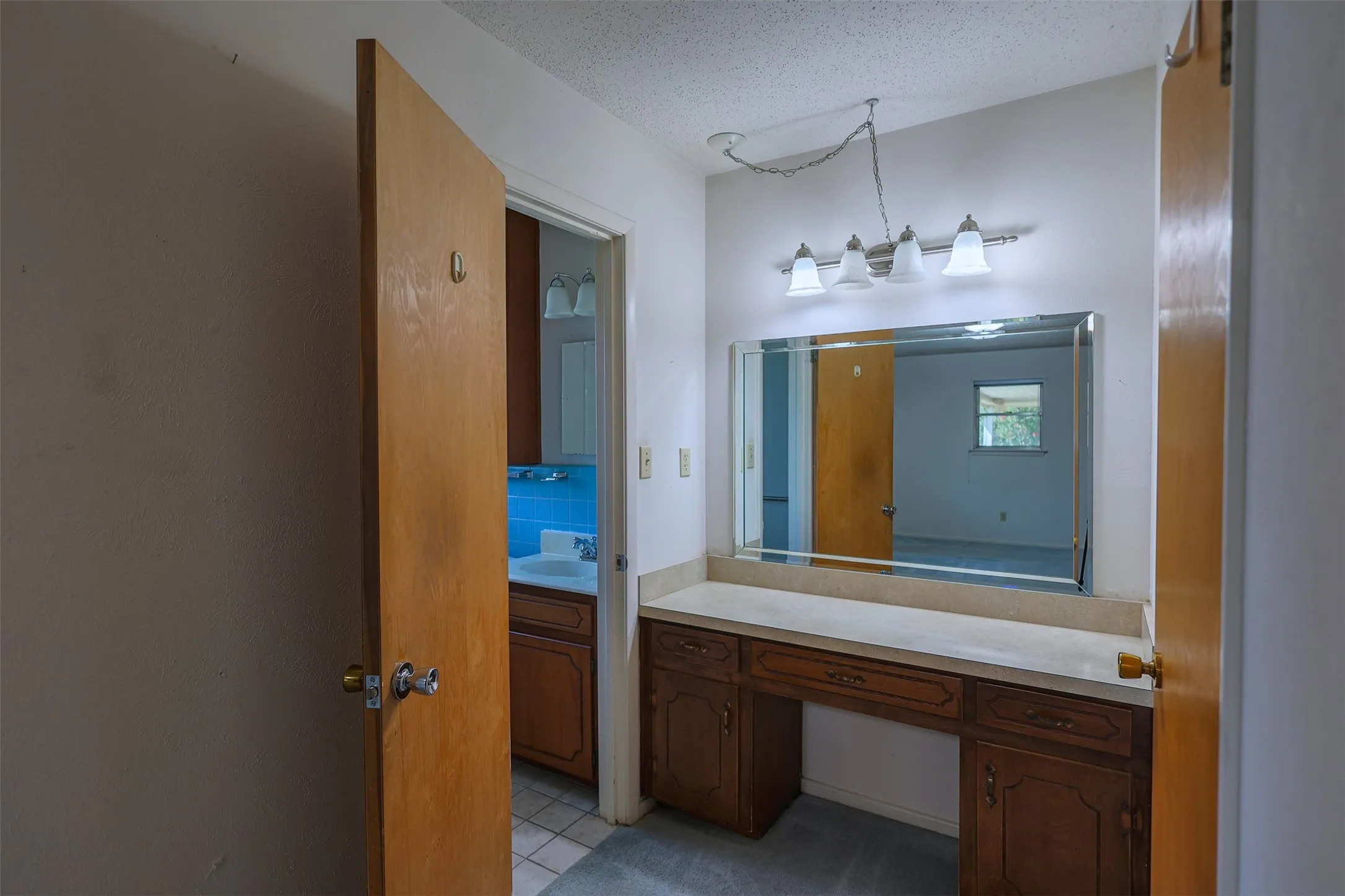 Vanity area featuring a built-in dressing table with wood cabinetry, a large wall-mounted mirror, and a four-light fixture