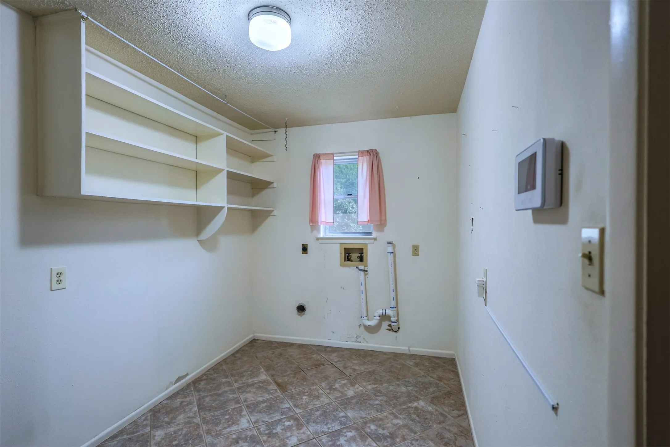 Utility room featuring integrated shelving and durable tile flooring