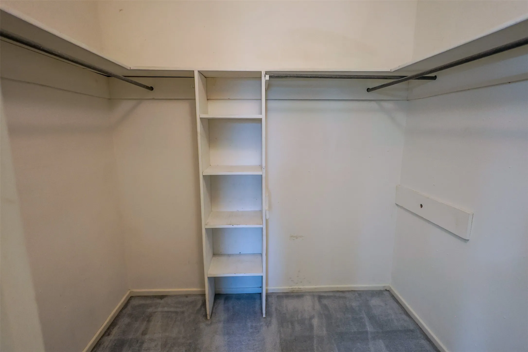 Walk-in closet featuring built-in shelving, dual hanging rods, and ample storage space