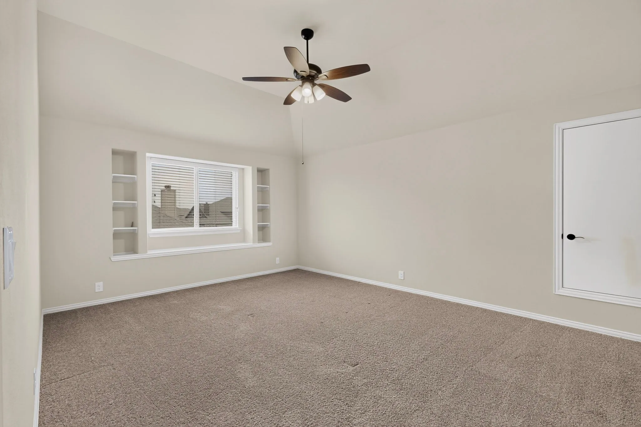 Spacious room featuring vaulted ceilings, neutral-toned carpeting, and a ceiling fan with integrated lighting