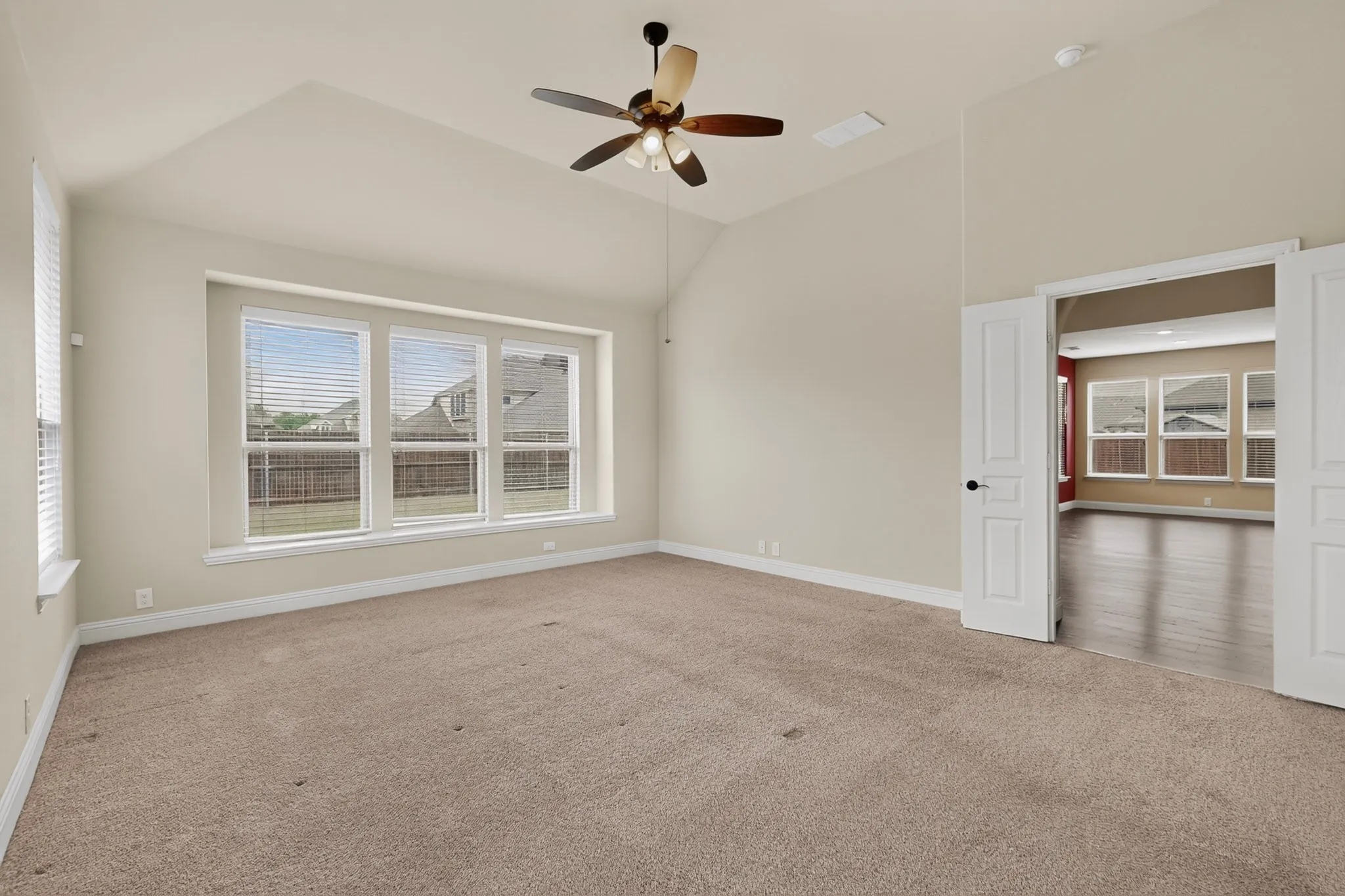 Spacious room featuring vaulted ceilings, a ceiling fan with integrated lighting, and carpet flooring