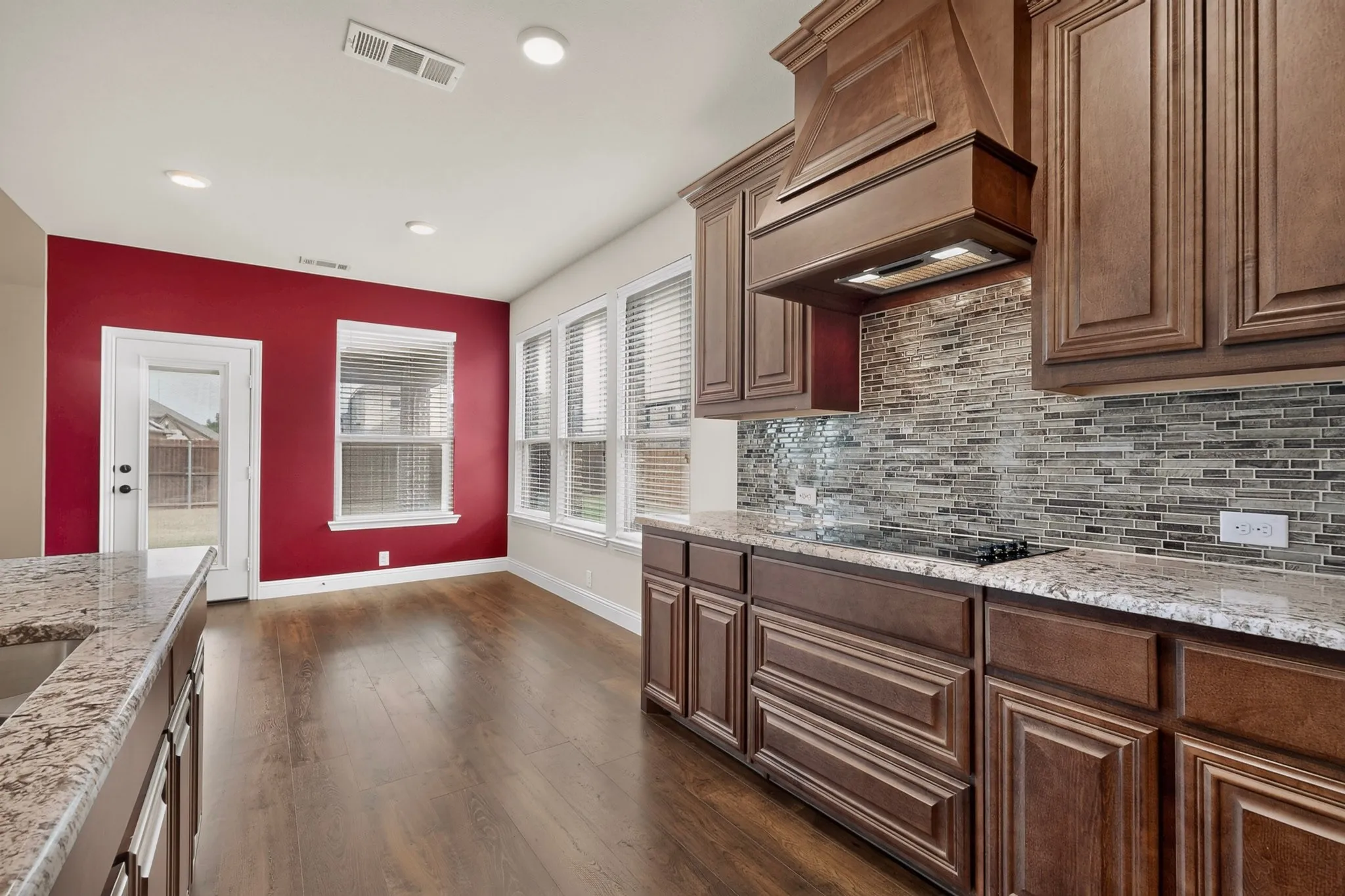 Kitchen area featuring wood-finish flooring, dark wood cabinetry, and a mosaic tile backsplash