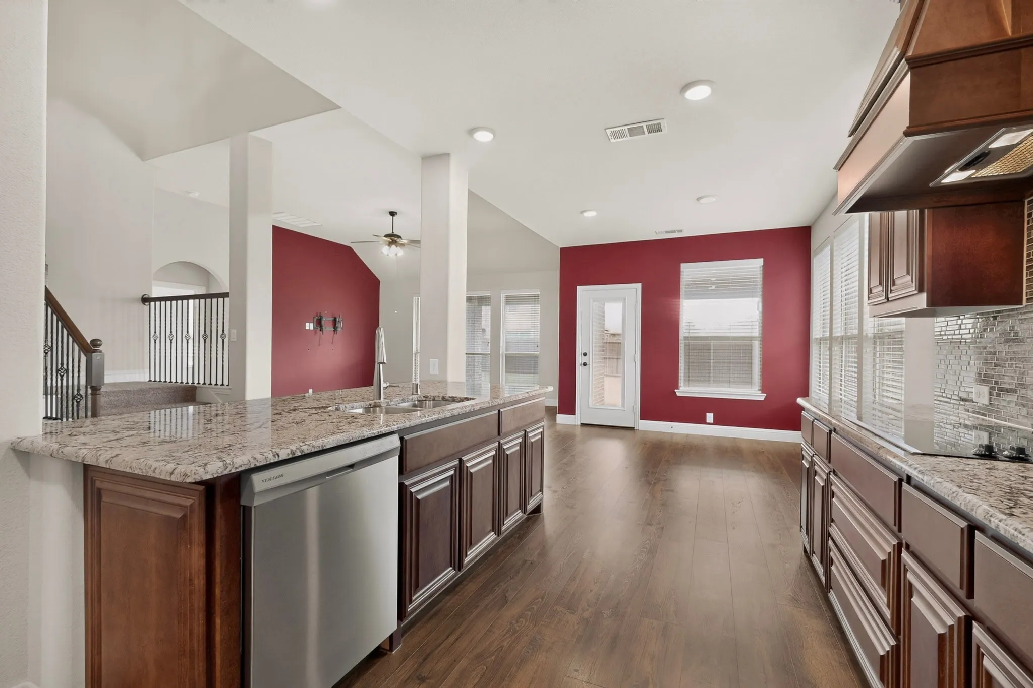 Kitchen featuring wood-finish flooring, granite countertops, dark wood cabinetry, and stainless steel appliances