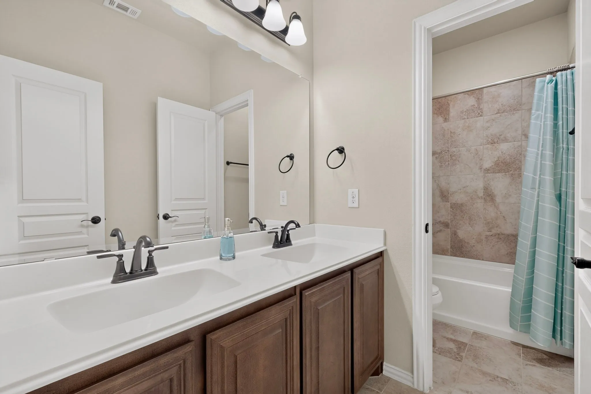 Dual vanity featuring undermount sinks, bronze finish hardware, and wood-finish cabinetry