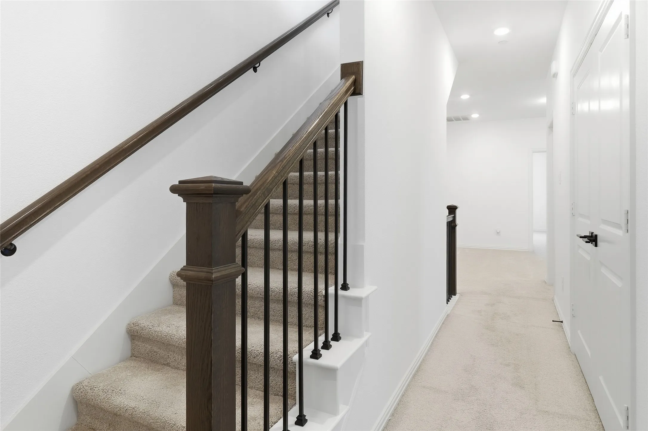 Modern staircase featuring dark wood newel posts and handrails with black metal balusters