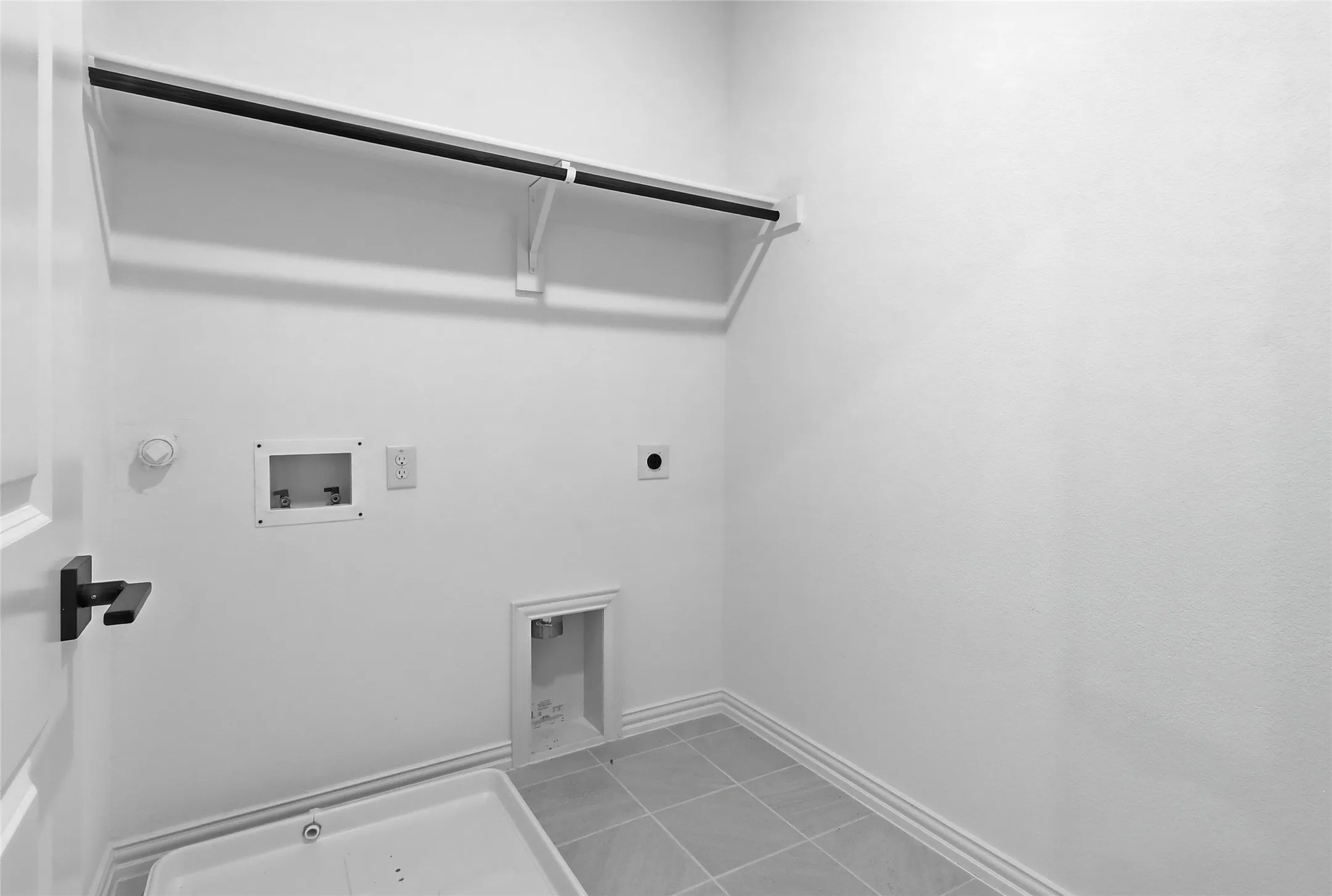 Dedicated laundry area featuring a utility sink, tiled flooring, wall-mounted connections, and an overhead clothes rod