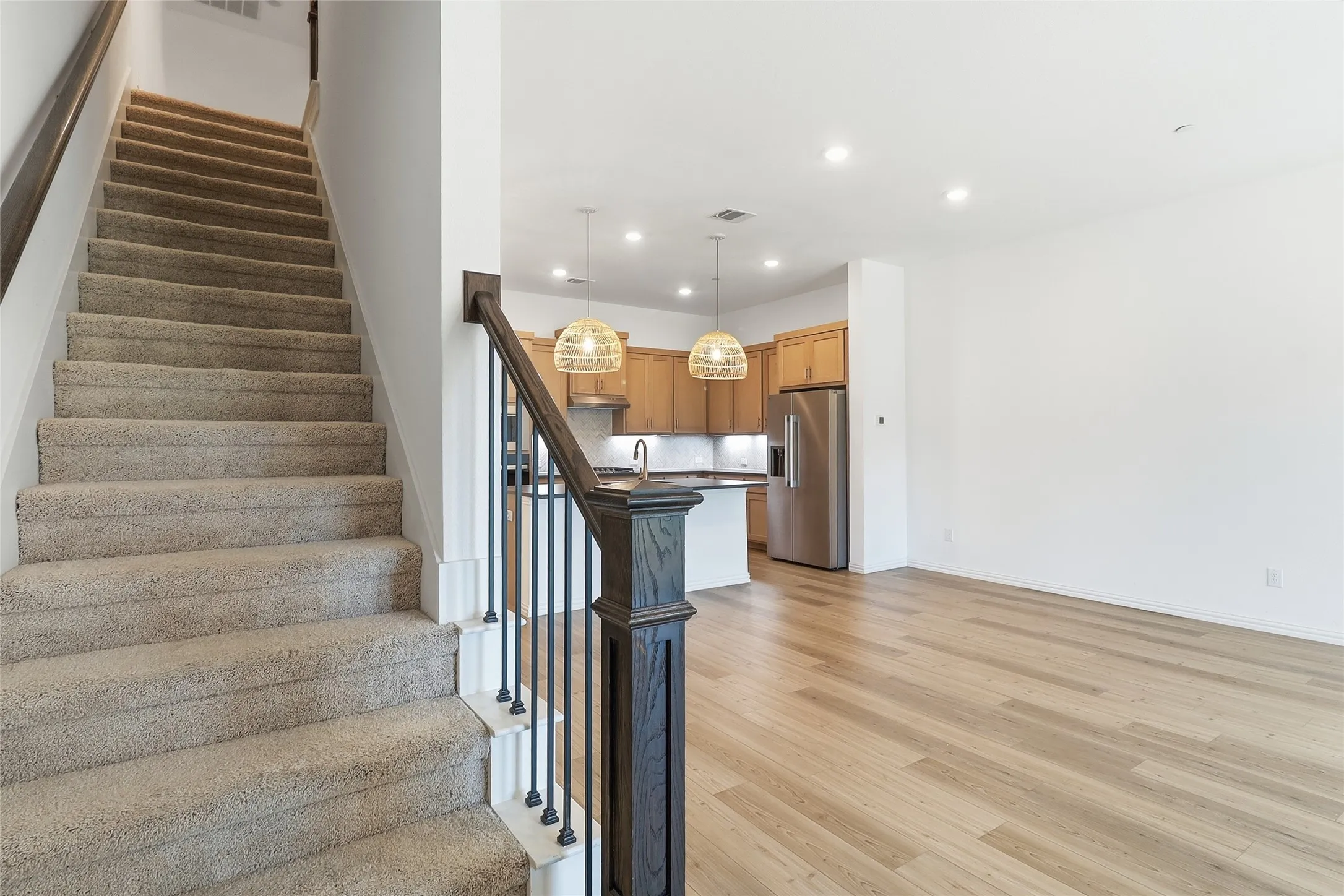 Carpeted staircase with dark wood newel post and metal balusters