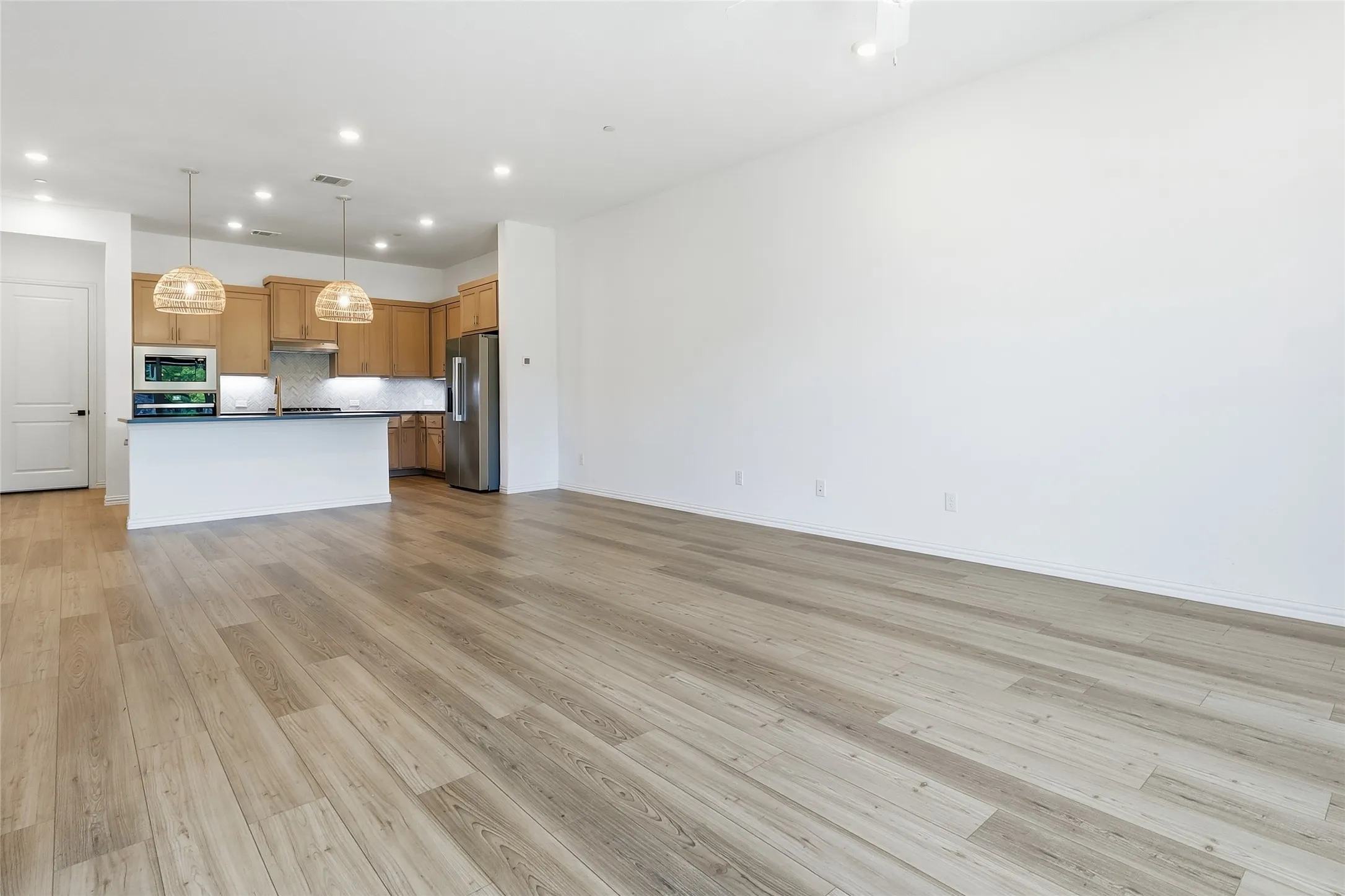 Open-concept living space featuring wood-finish flooring, recessed lighting, and a modern kitchen