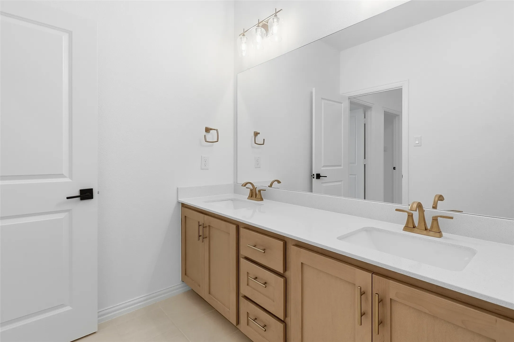 Dual vanity featuring light wood-finish cabinetry and white countertops