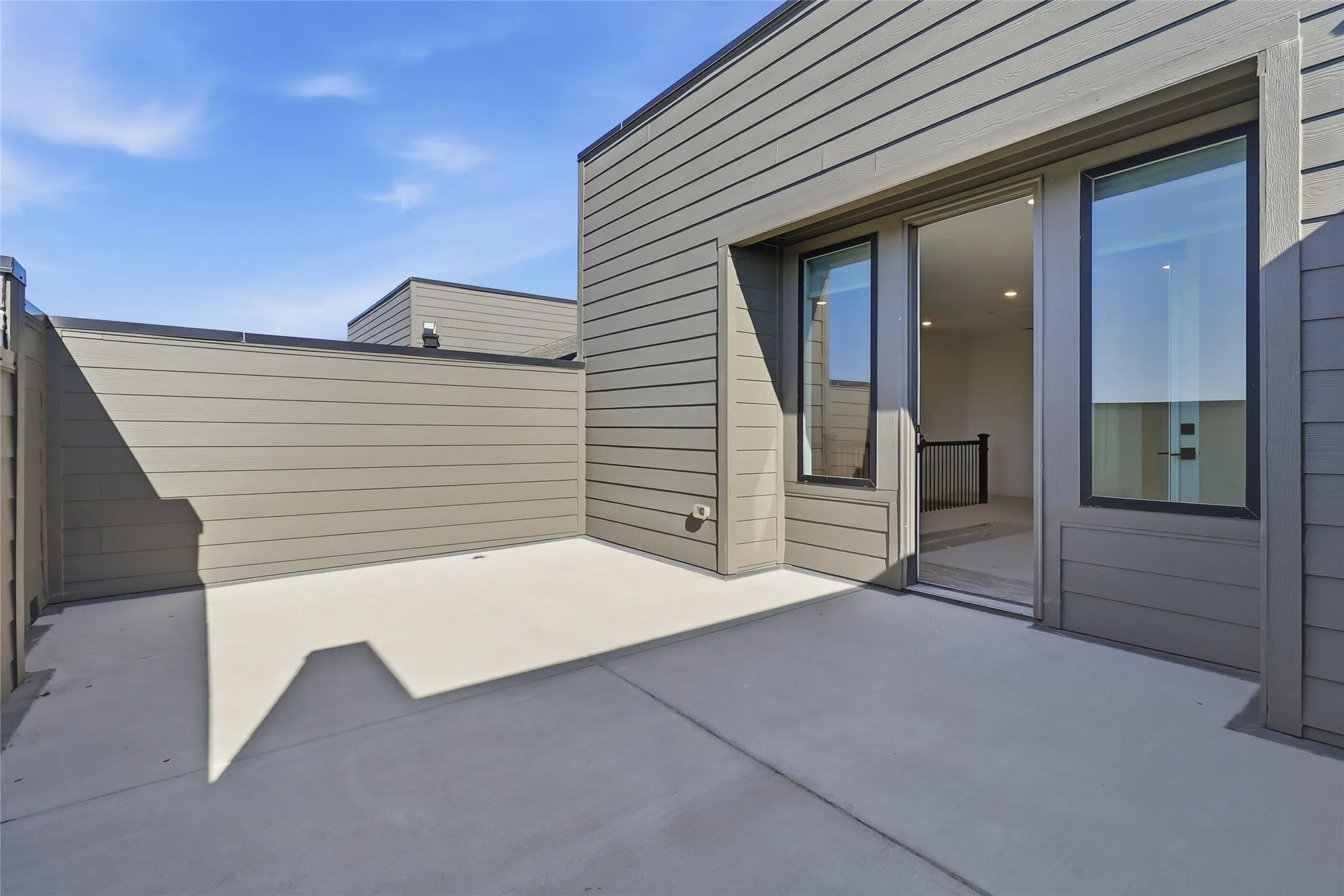 Spacious outdoor patio with composite siding and a glass sliding door entry