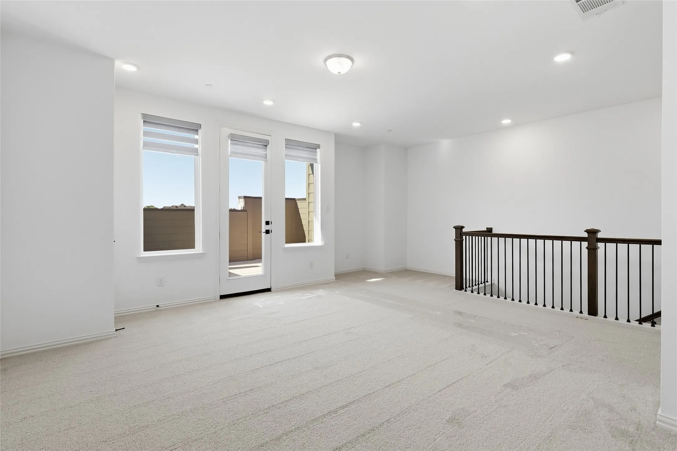 Spacious room featuring light-colored carpeting and white walls