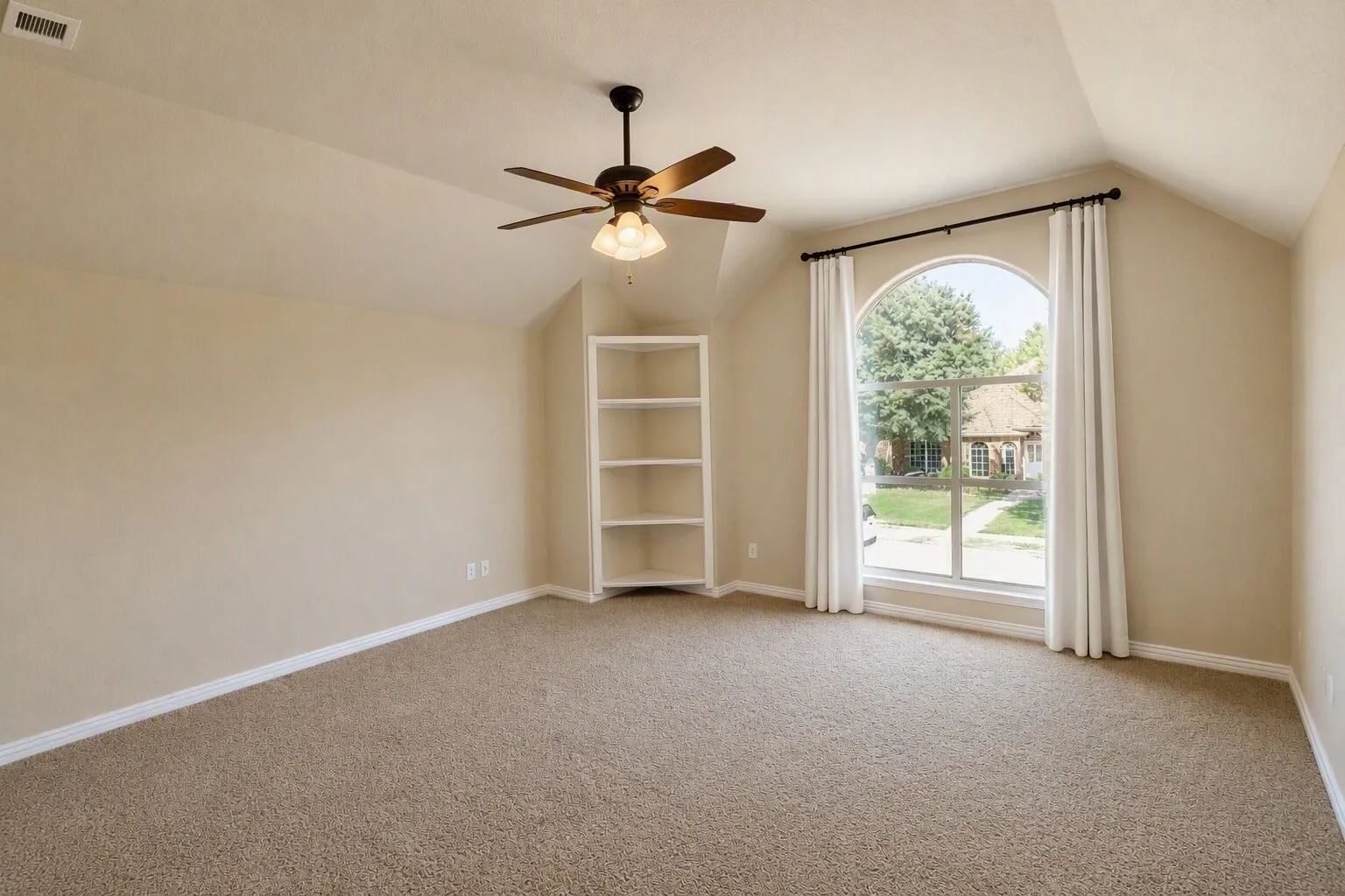 Arched window, built-in shelving, ceiling fan, and carpeted flooring