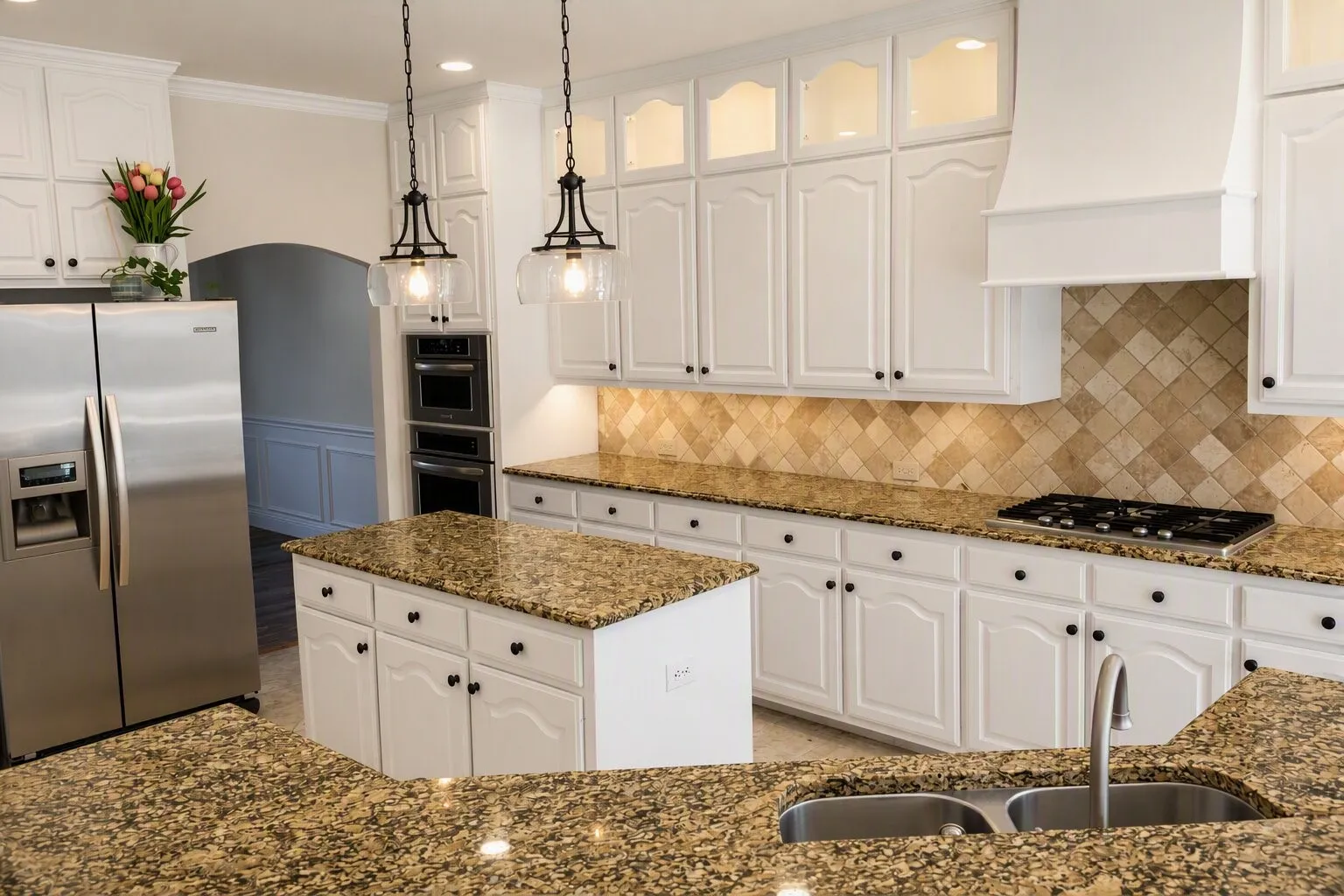Kitchen featuring white cabinetry, granite  countertops, stainless steel appliances, a tiled backsplash, and pendant lighting