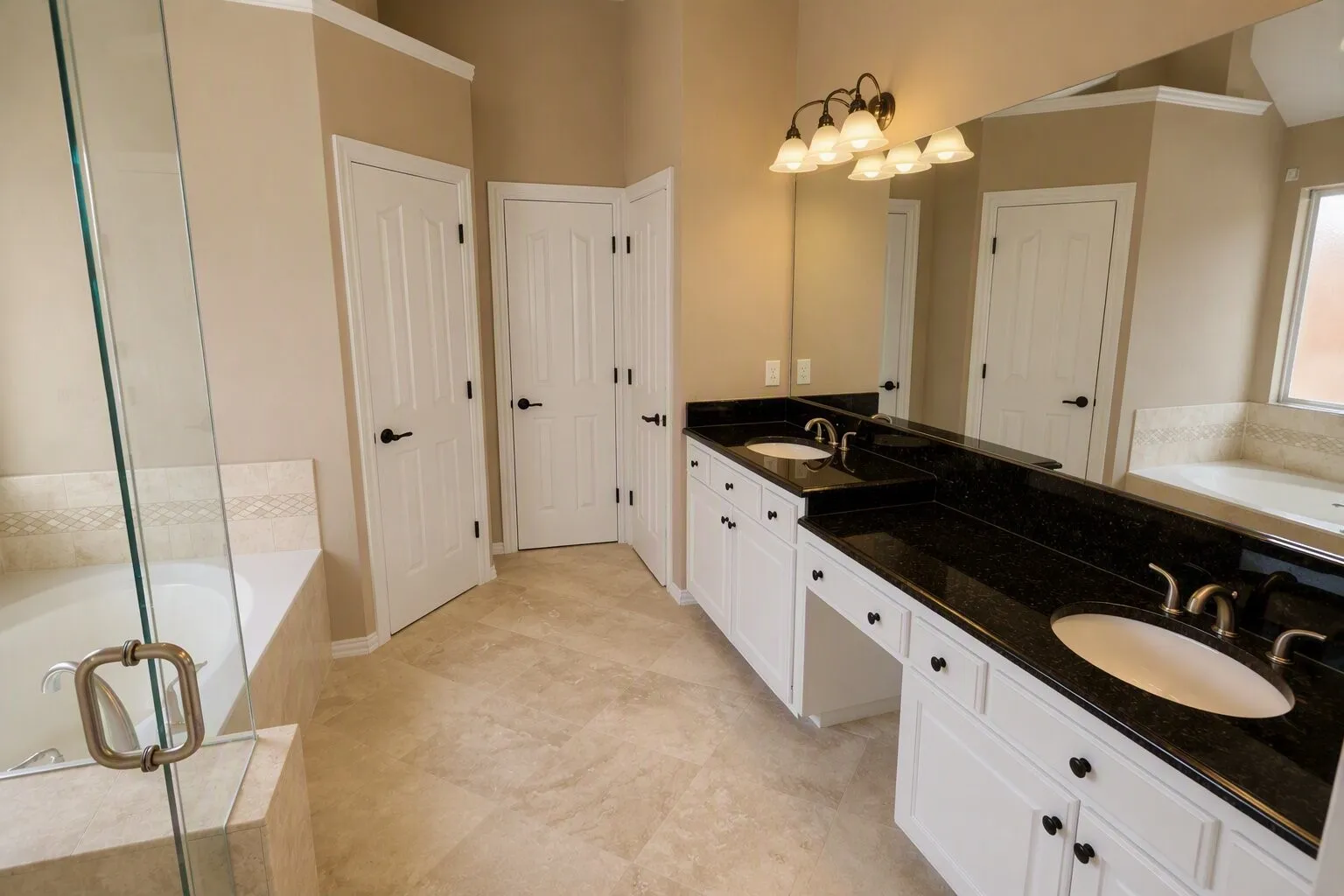 Dual vanity with dark granite countertops, a built-in makeup area, and individual sinks