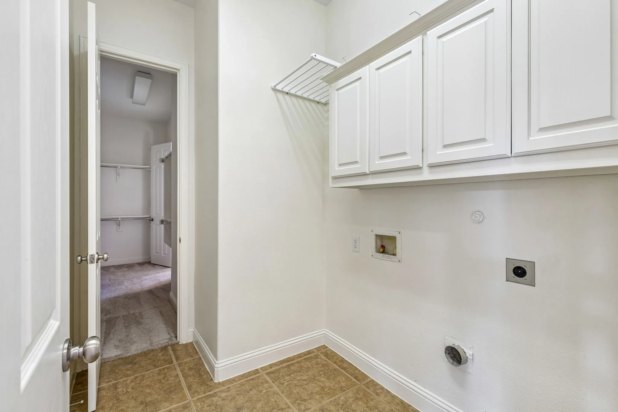 Laundry room with access to primary closet