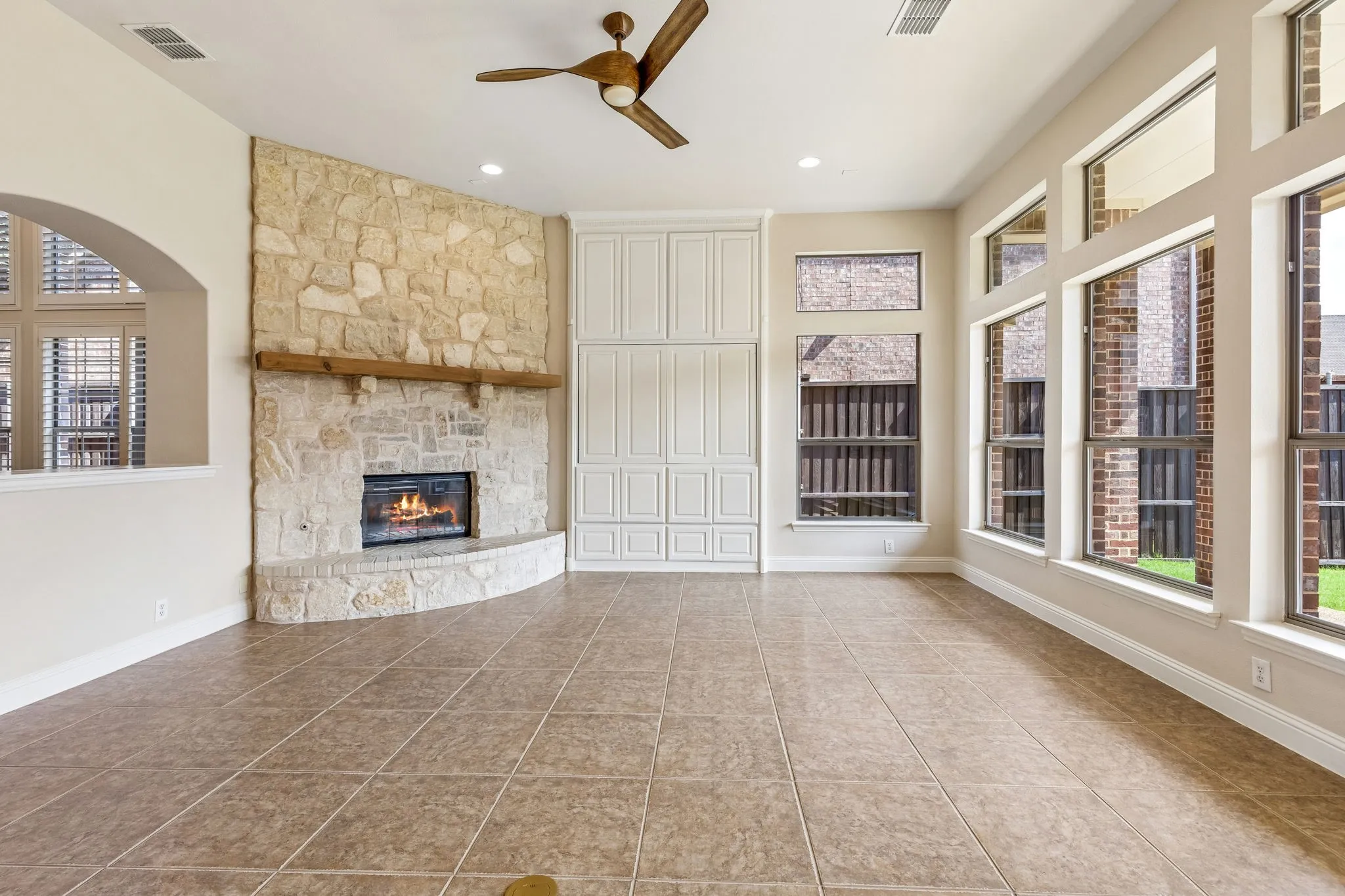 Stone-clad fireplace with wood mantle, built-in cabinetry and expansive window wall