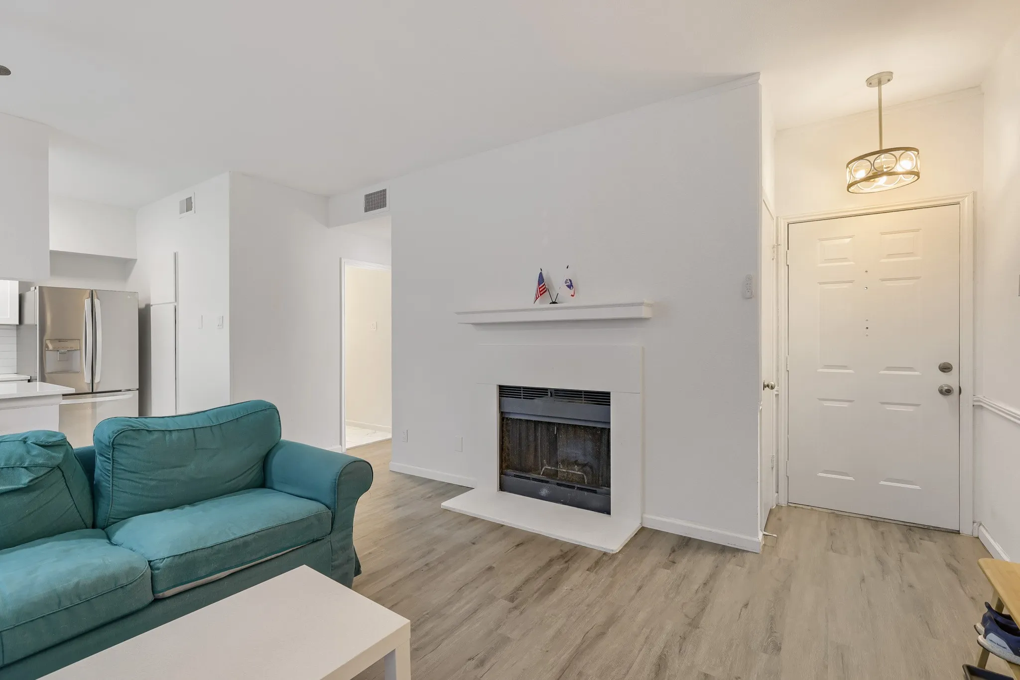 Living area featuring light wood-finish flooring and a fireplace with a white mantel and hearth