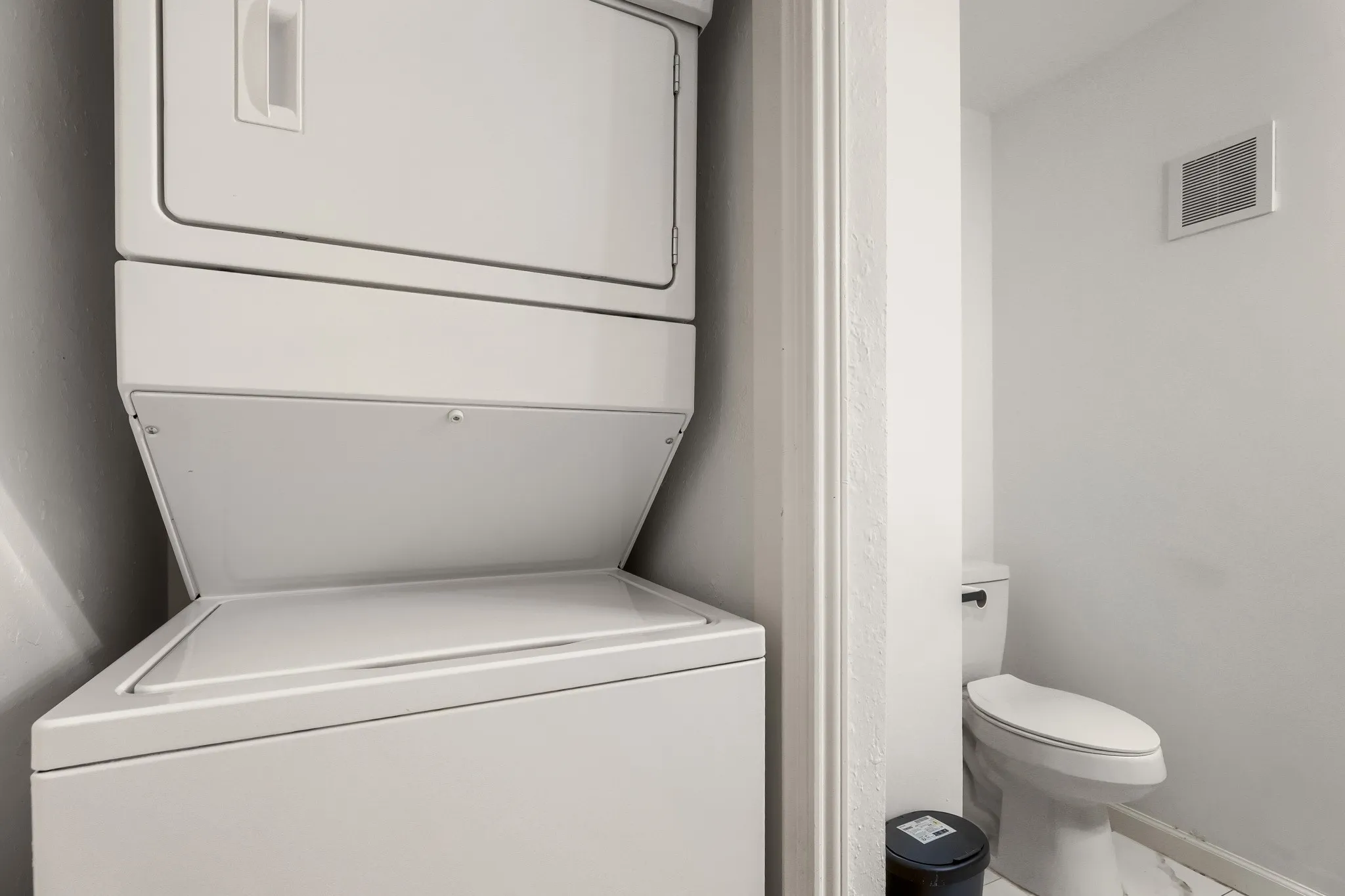 Dedicated laundry area in the half bath, comes with a stacked washer and dryer