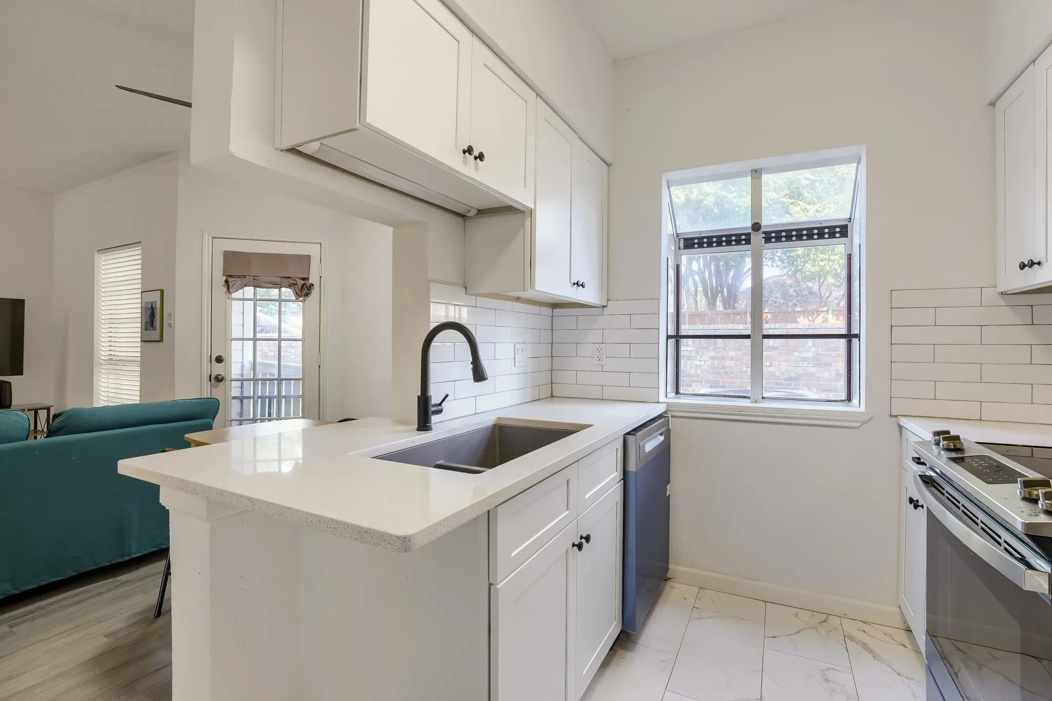 Kitchen featuring white cabinetry, quartz-finish countertops, subway tile backsplash, and a stainless steel appliance suite