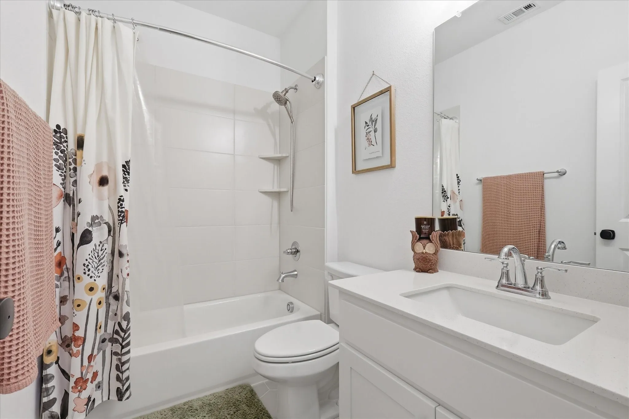Bathroom featuring a built-in tub with tile surround, white vanity with integrated sink, and a large wall-mounted mirror