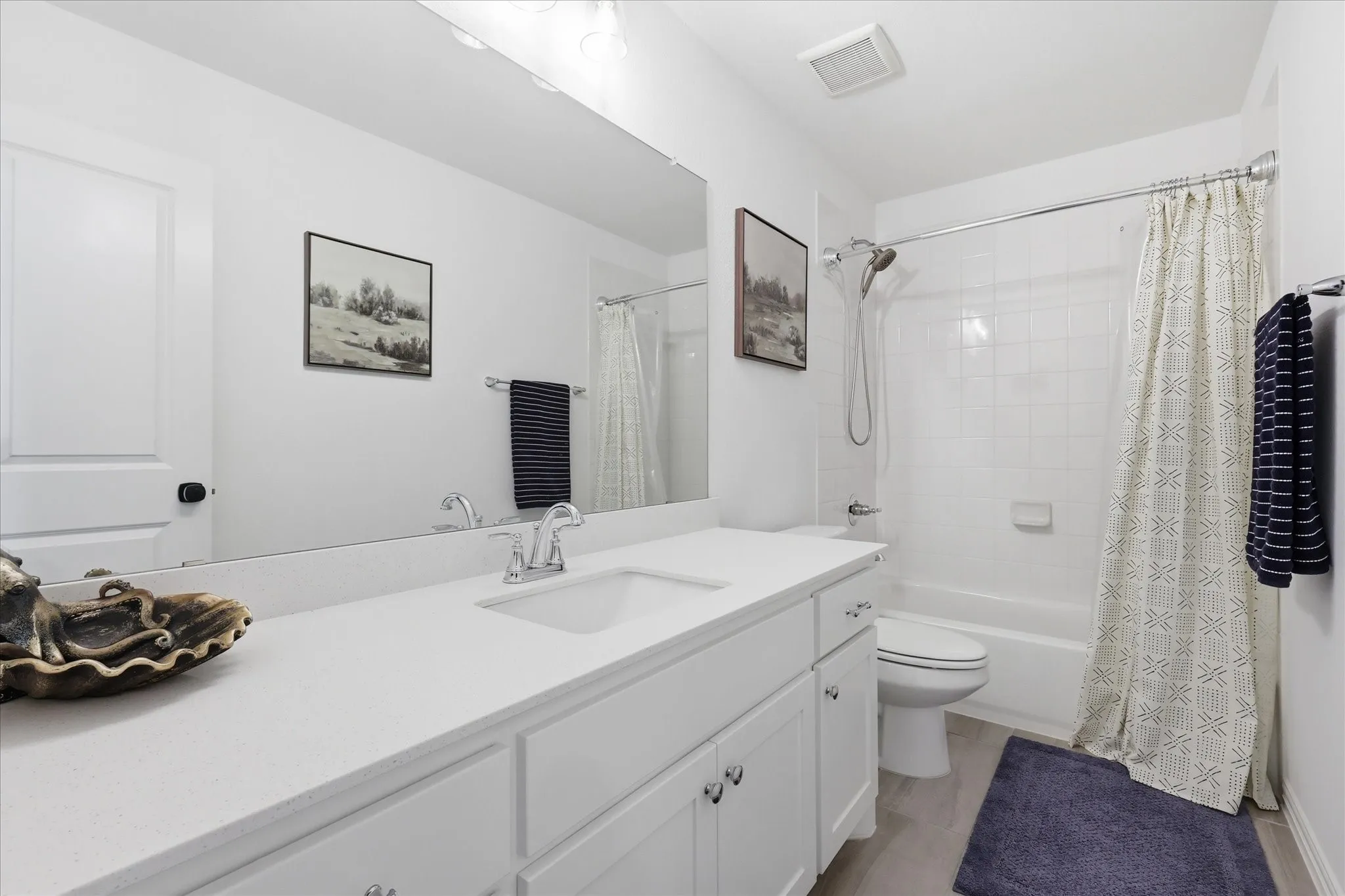 Bathroom featuring a white vanity with an integrated sink, polished chrome faucet, and expansive wall-mounted mirror