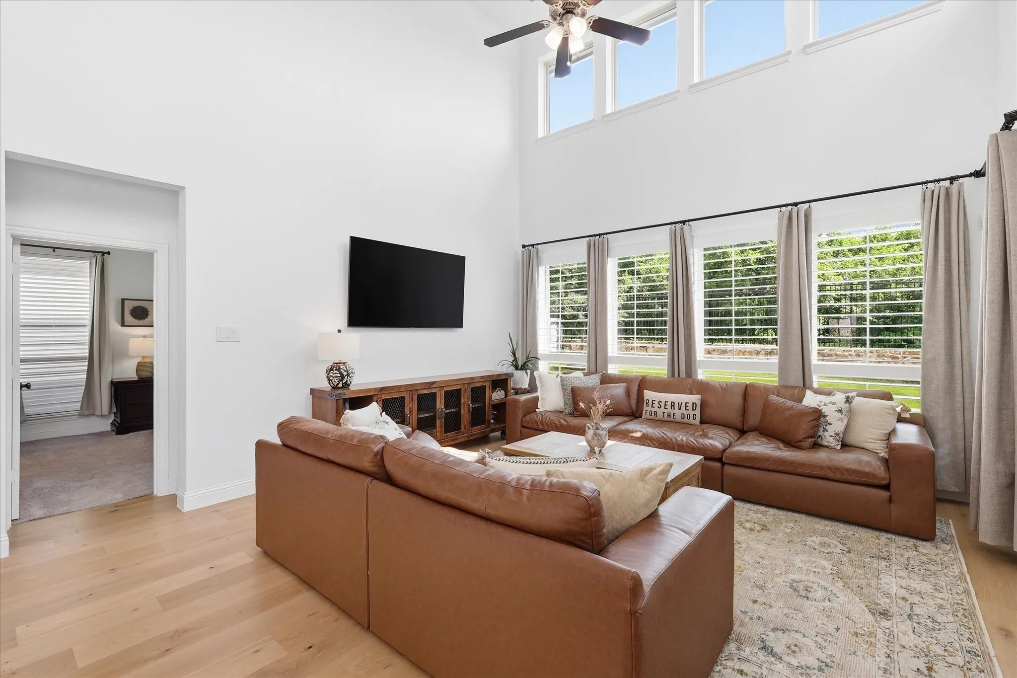 Living area featuring high ceilings, upper transom windows, a ceiling fan, and wood-finish flooring