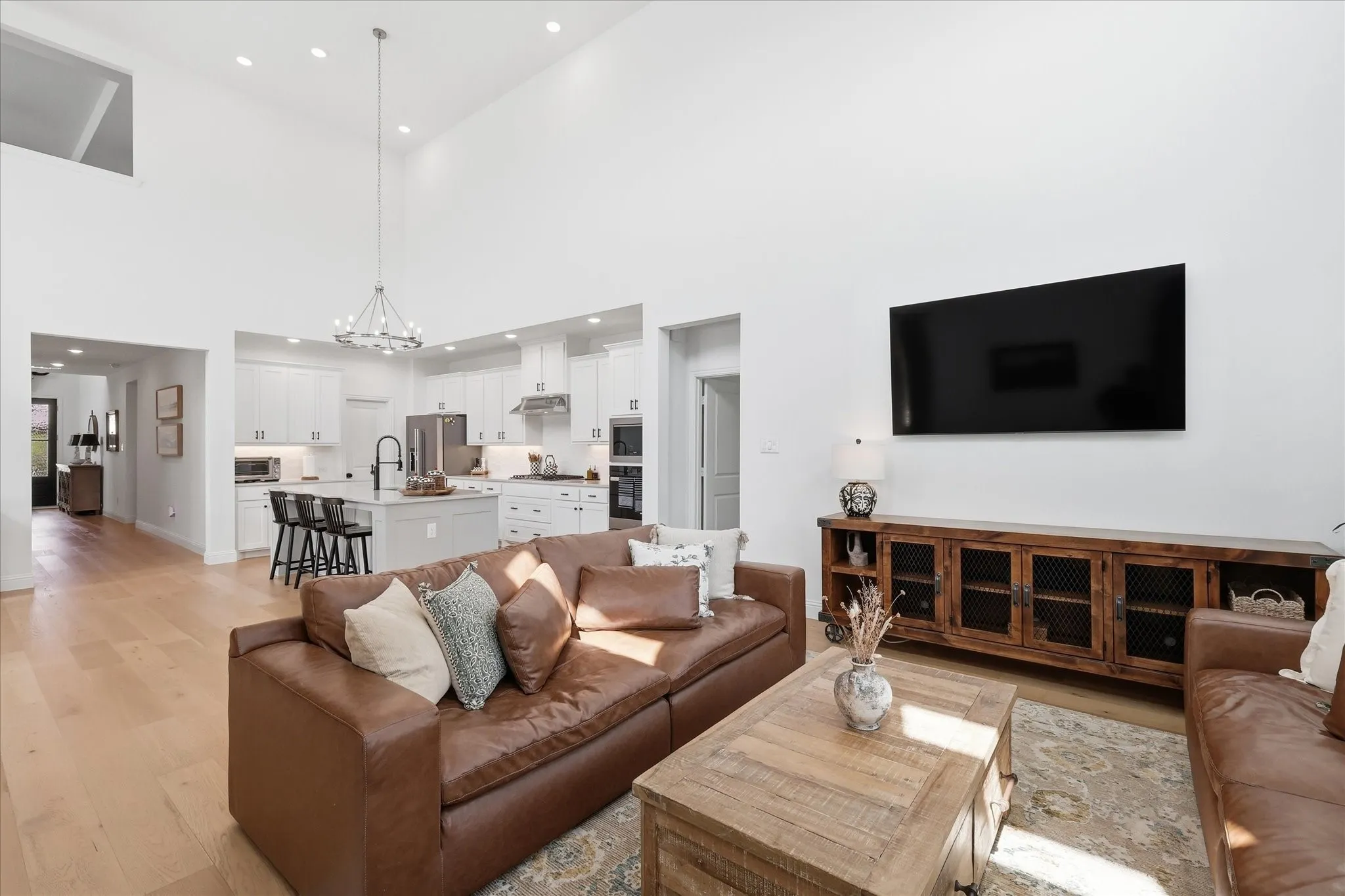 Vaulted ceiling great room featuring wood-finish flooring, recessed lighting, and a contemporary chandelier