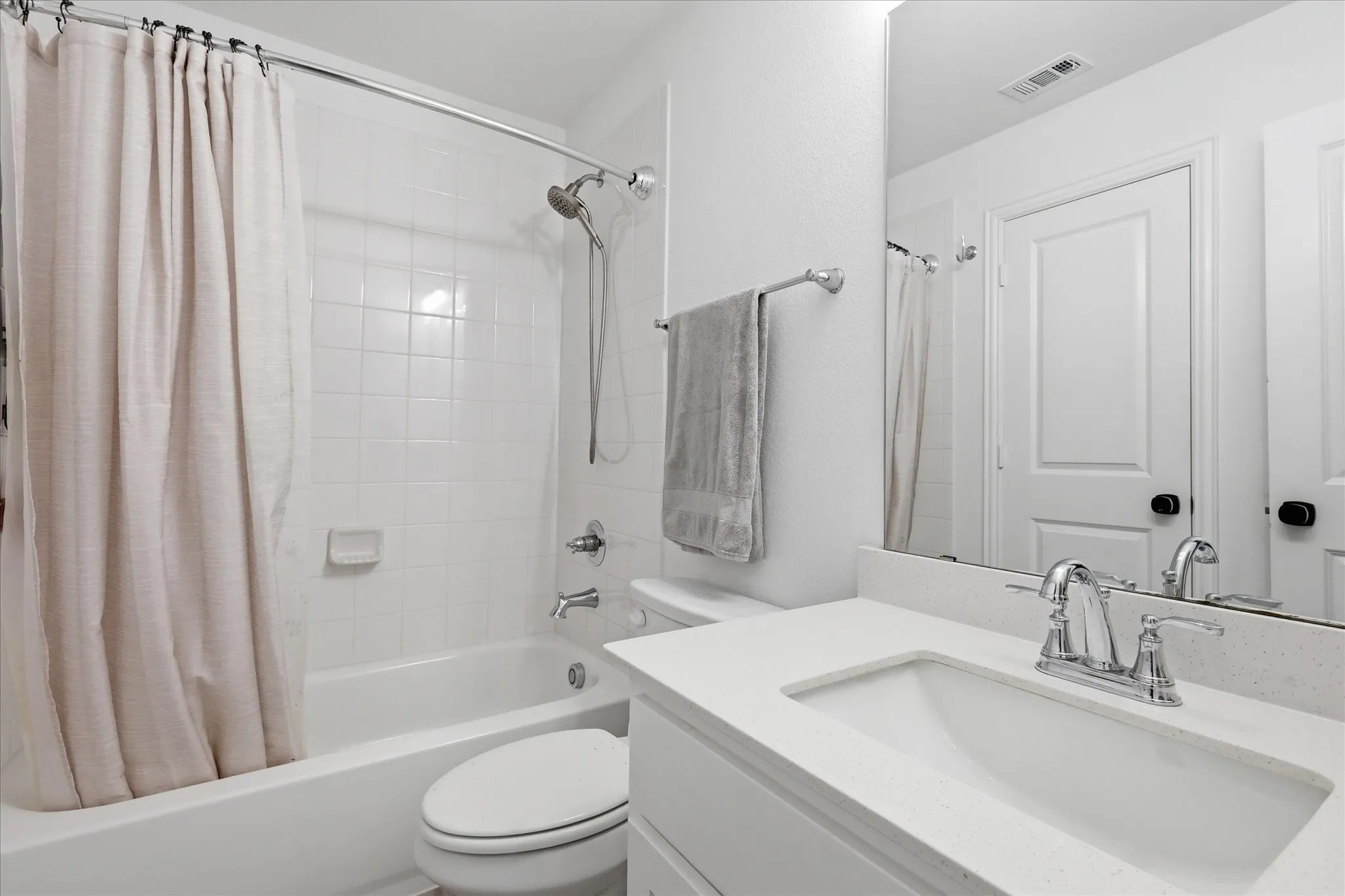 Full bathroom featuring a single vanity with a solid surface countertop, an undermount sink, and a chrome faucet