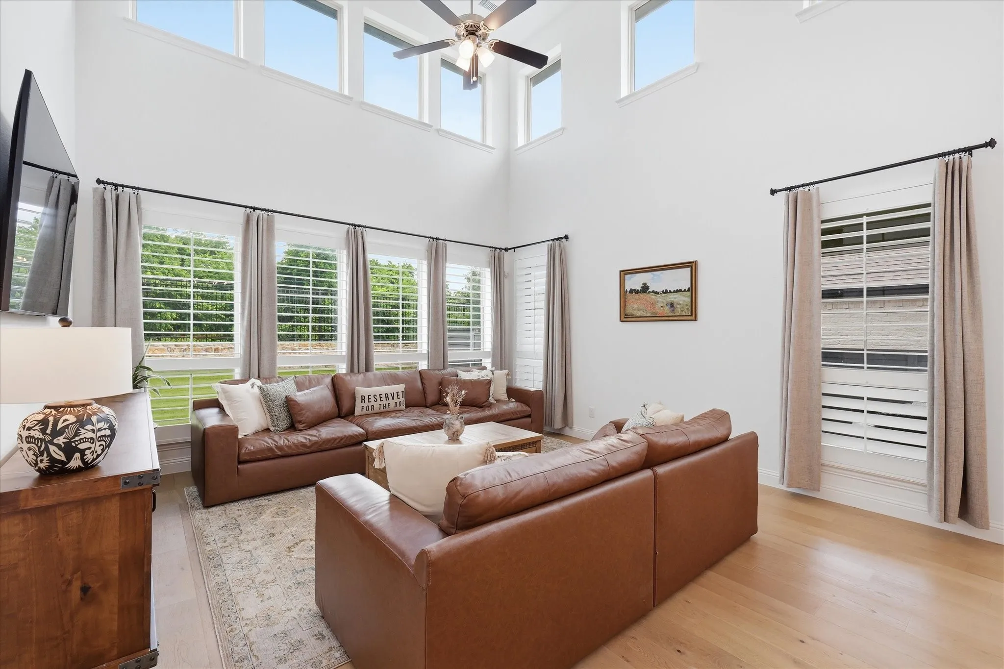 Two-story living area featuring high ceilings, multiple upper transom windows, and a ceiling fan