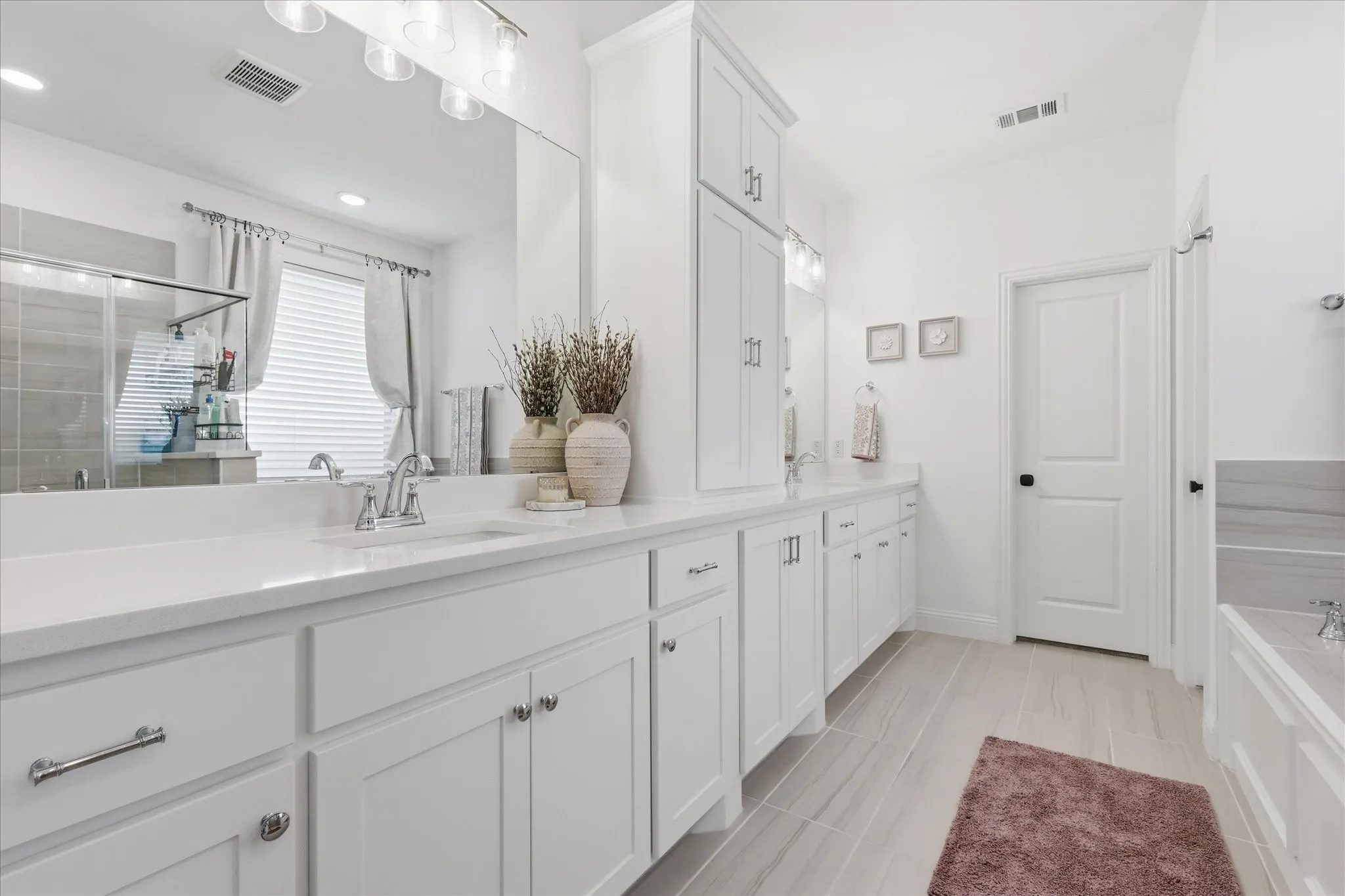 Spacious bathroom featuring a double vanity with ample counter space, white cabinetry, and a large wall-mounted​​‌​​​​‌​​‌‌​‌‌​​​‌‌​‌​‌​‌​​​‌​​ mirror