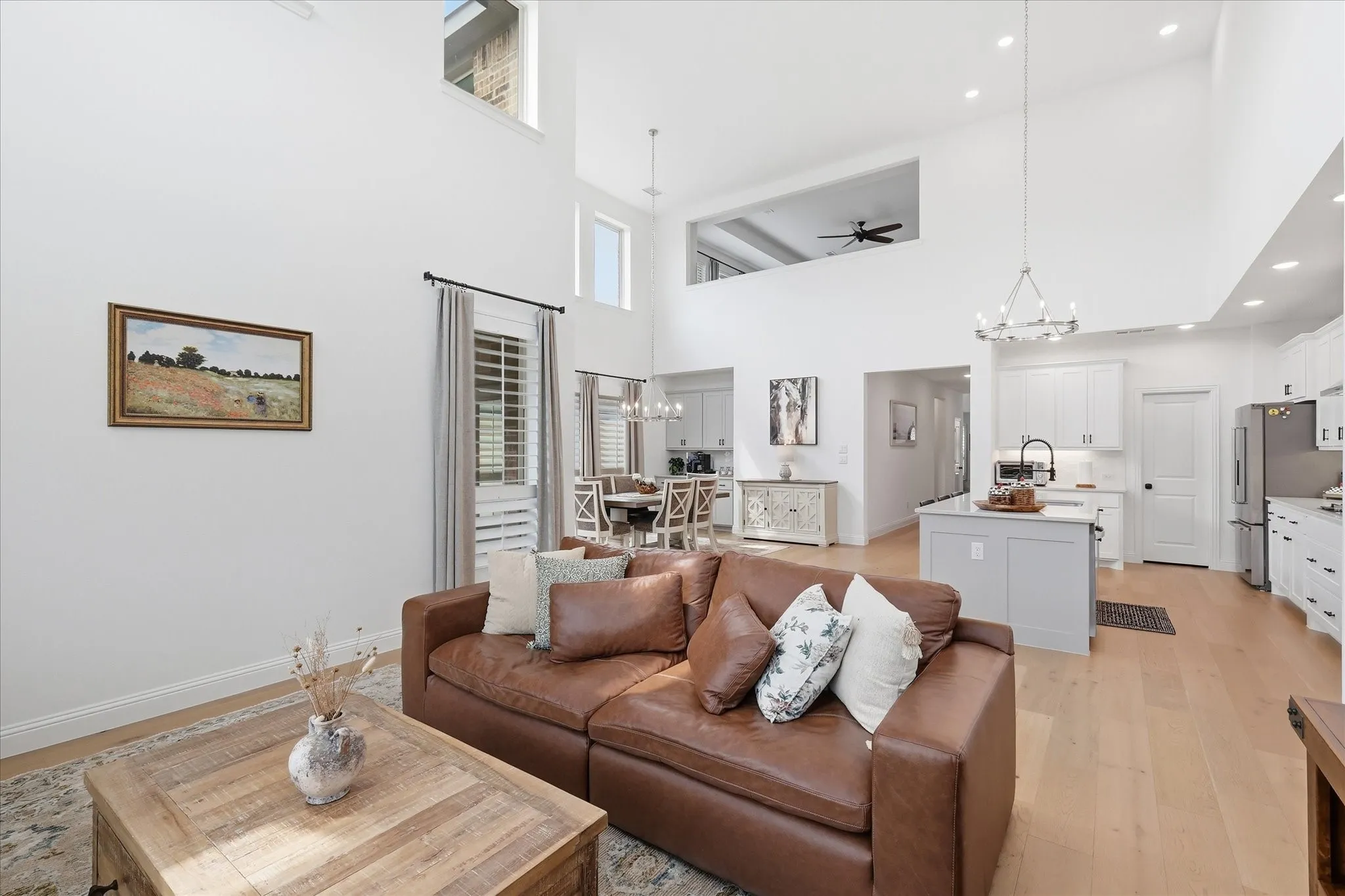 Great room with soaring ceilings, wood-finish flooring, and bright white walls