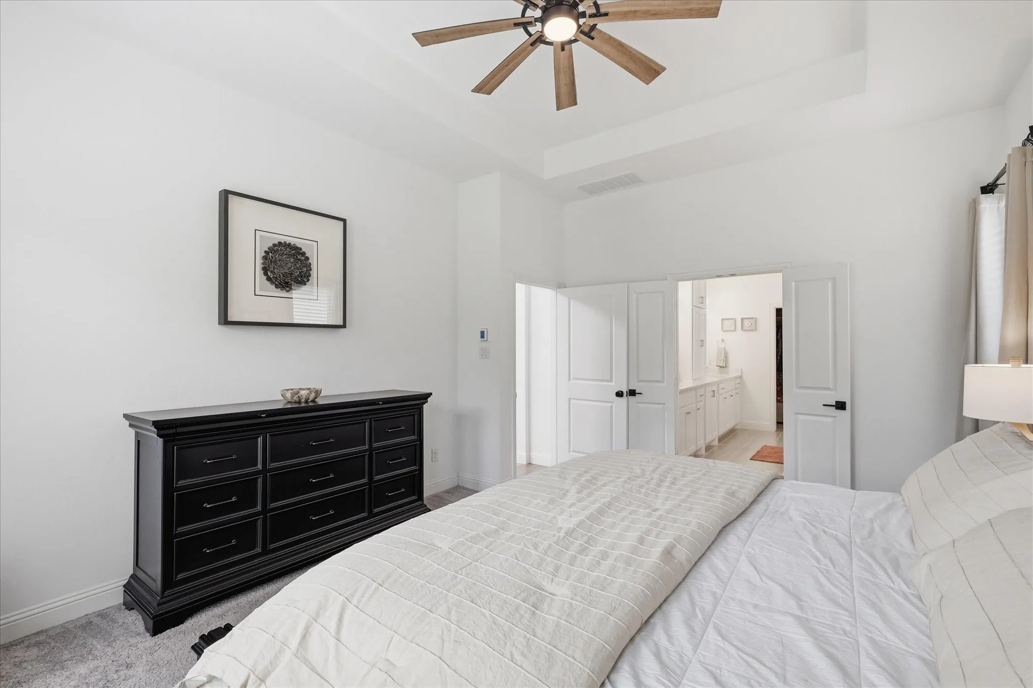 Spacious room featuring a tray ceiling with a ceiling fan, plush carpet, and white walls