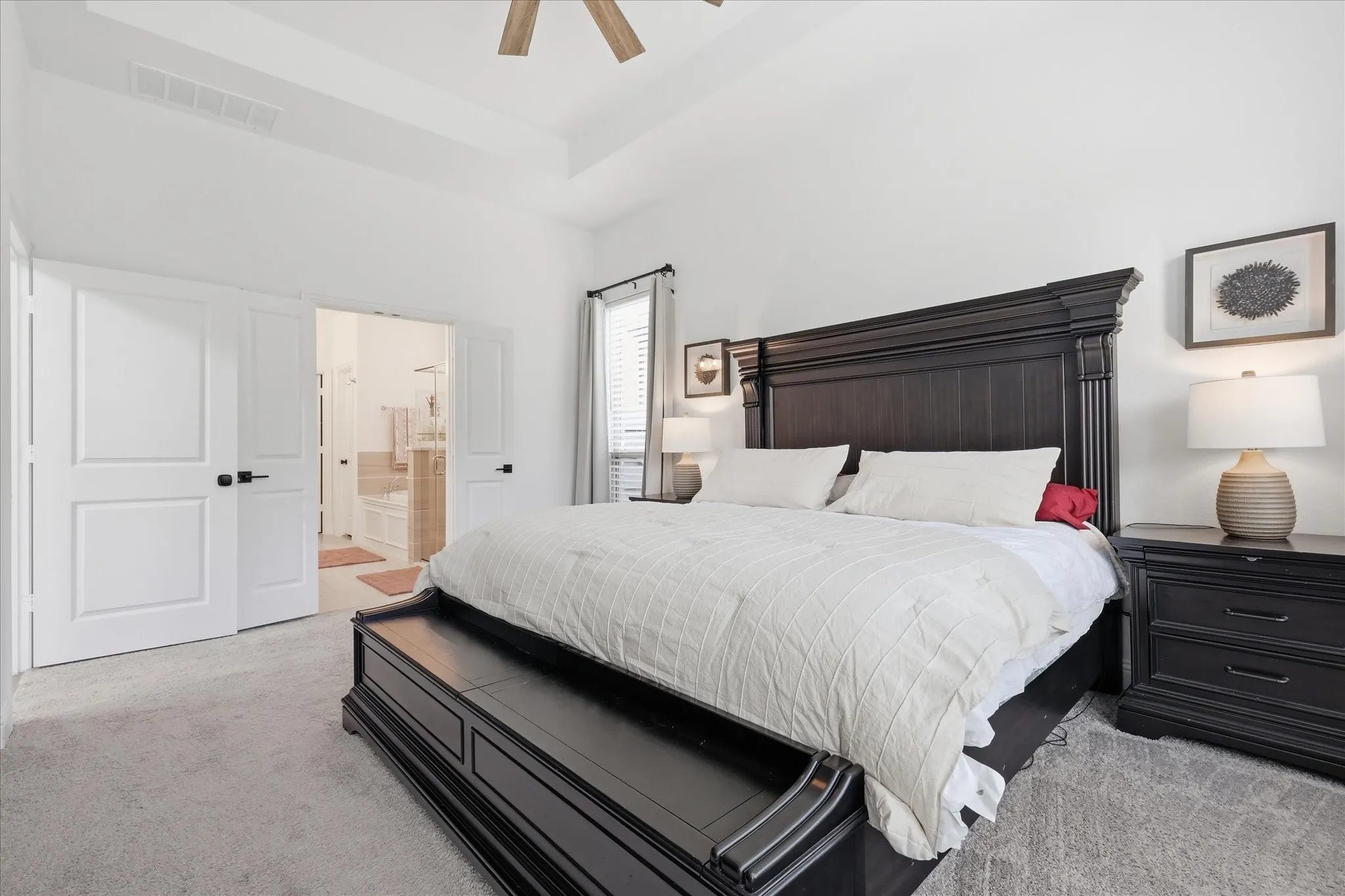 Spacious bedroom featuring light gray carpeting and a tray ceiling