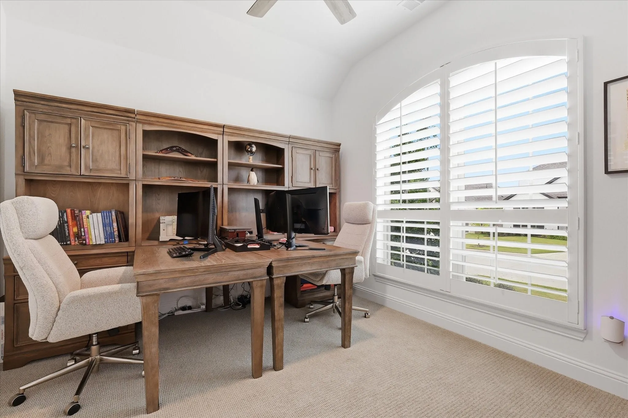 Arched window with plantation shutters, built-in wooden cabinetry, recessed lighting, and a ceiling fan