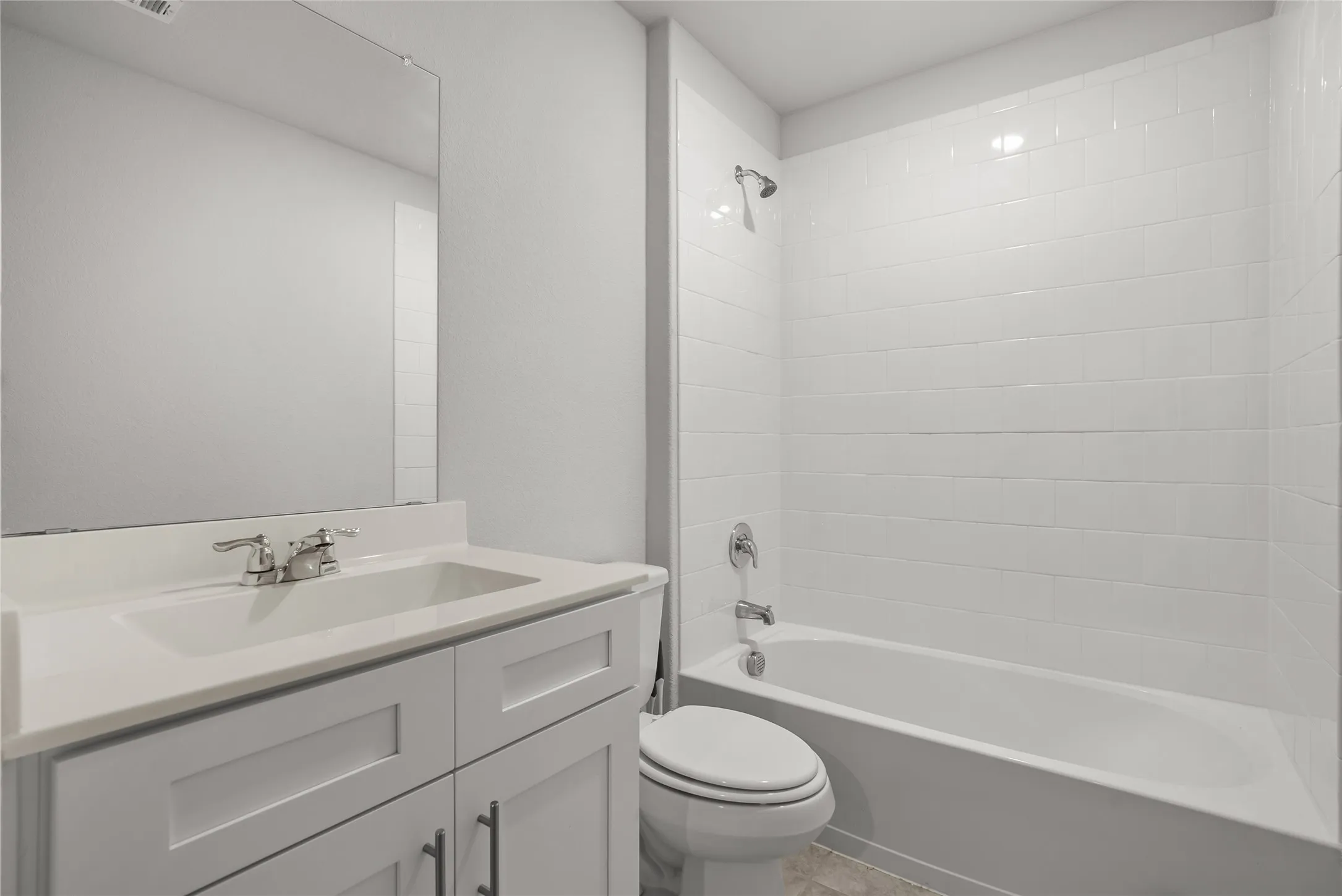 Bathroom featuring a white vanity with an integrated sink, polished chrome faucet, and a large wall-mounted mirror