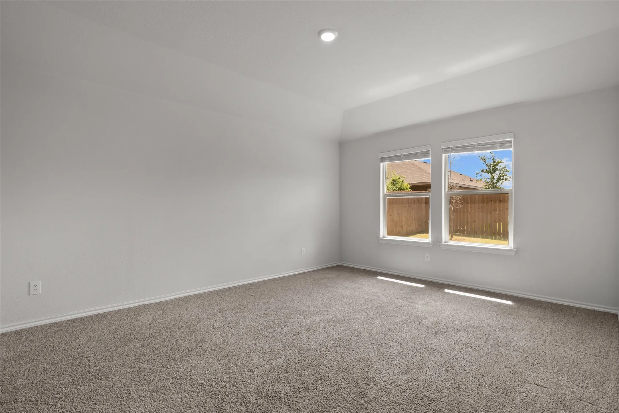 Carpeted interior room with light gray walls, two windows, and a recessed ceiling light