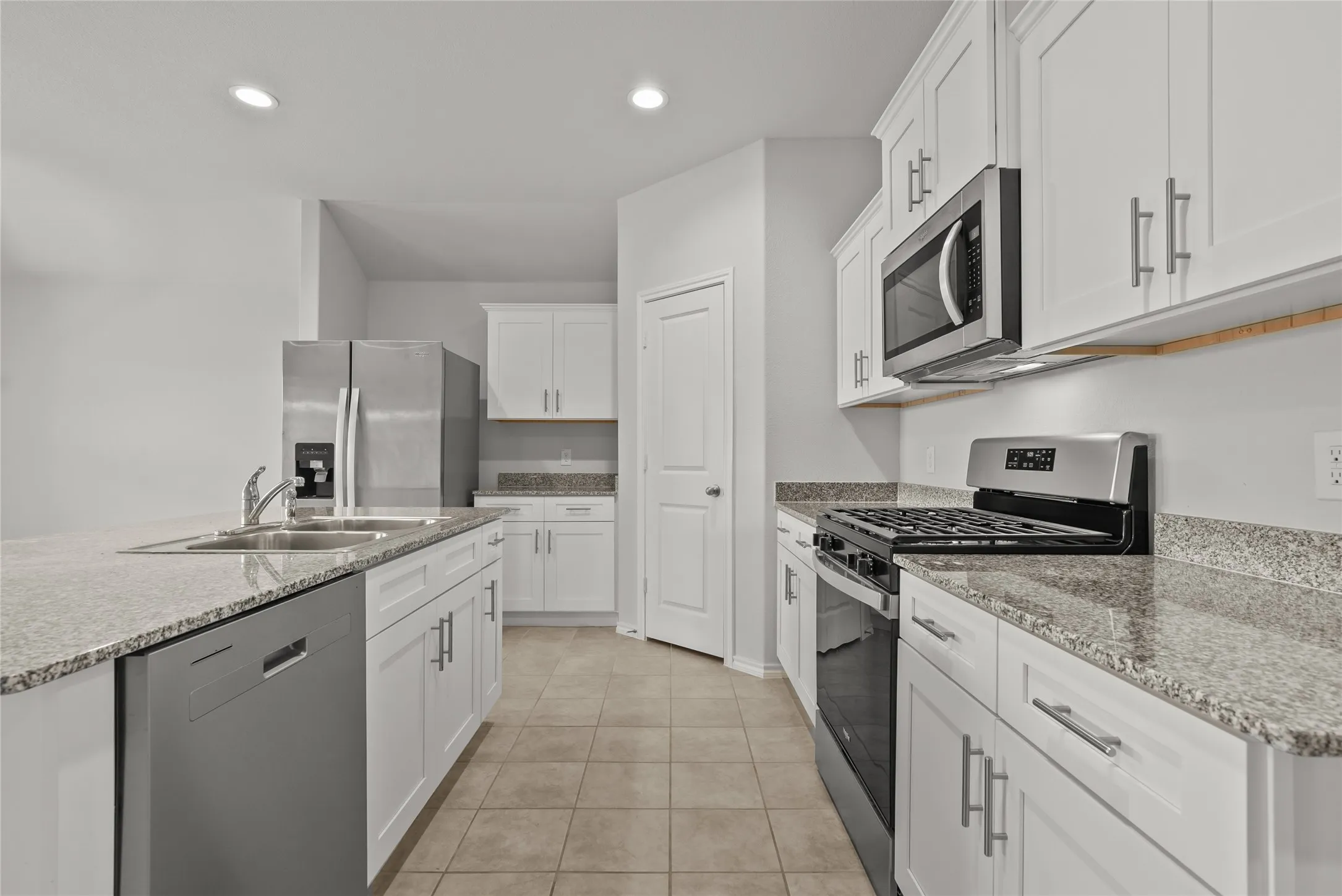 Kitchen featuring granite countertops, white cabinetry, stainless steel appliances, recessed lighting, and tile flooring