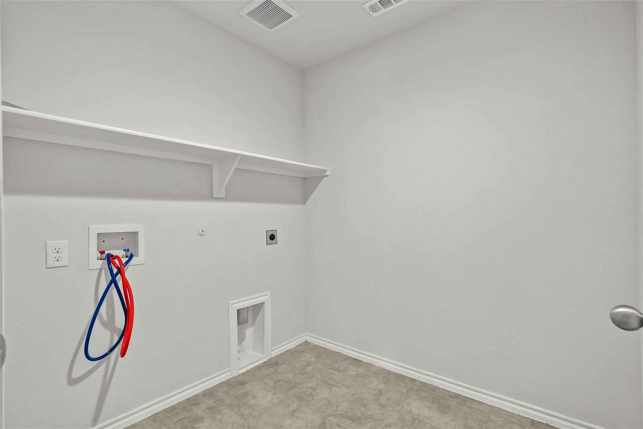 Dedicated laundry space featuring a utility hookup, overhead shelving, and baseboard trim