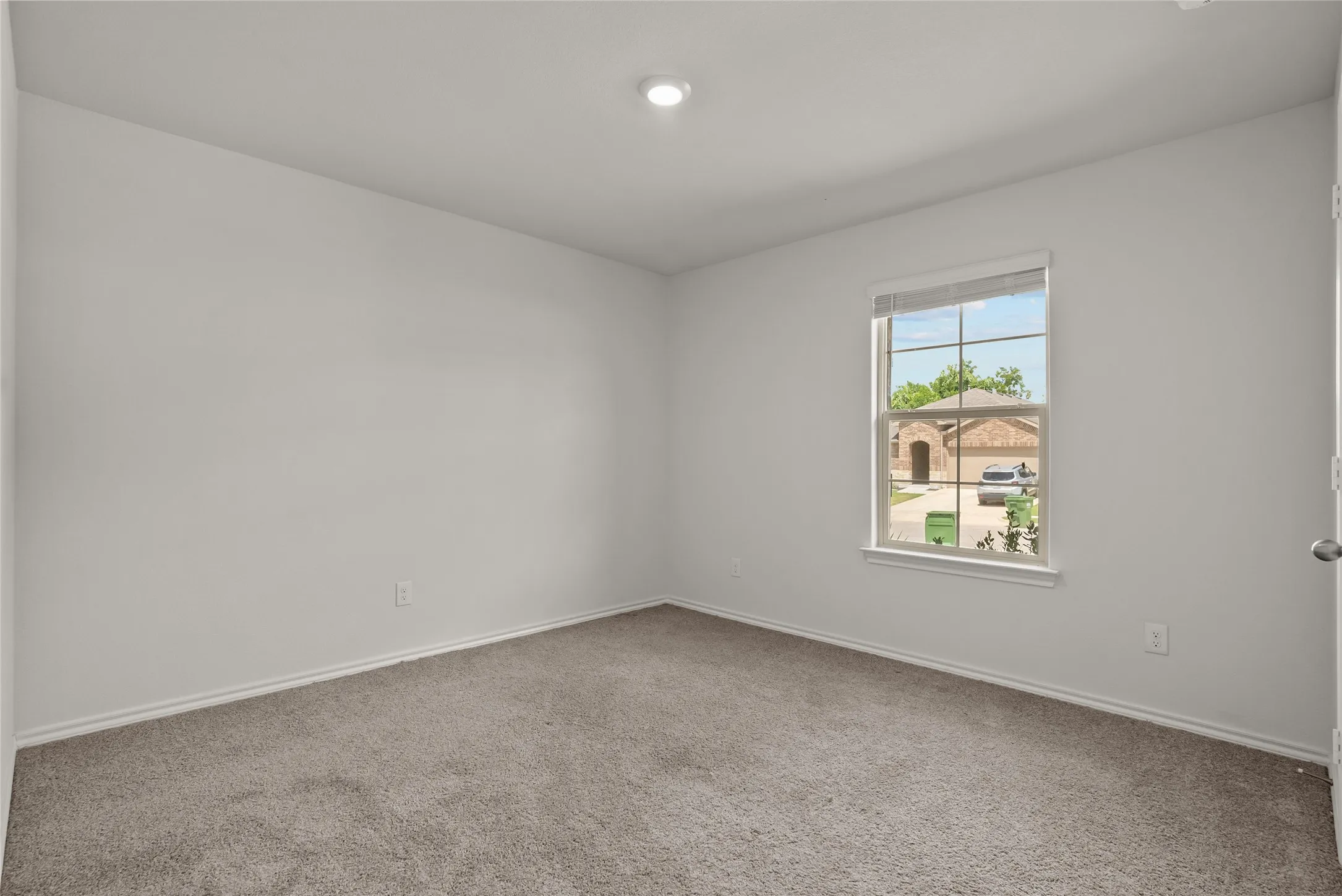 Carpeted room featuring a single window with blinds, white trim, recessed ceiling lighting, and light-colored walls