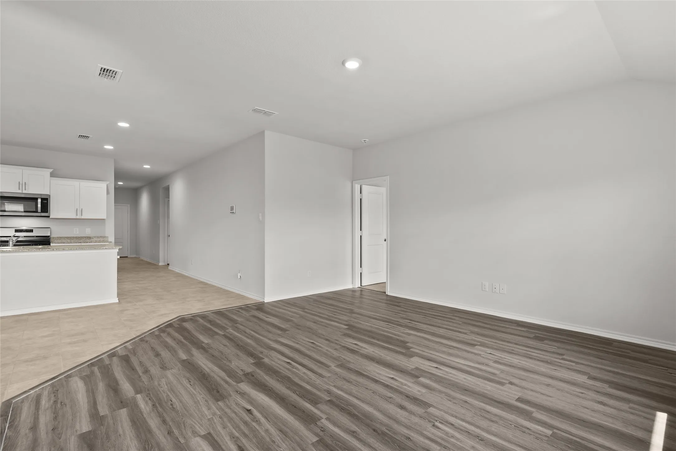 Open concept living area featuring wood-finish flooring, recessed lighting, and crisp white walls