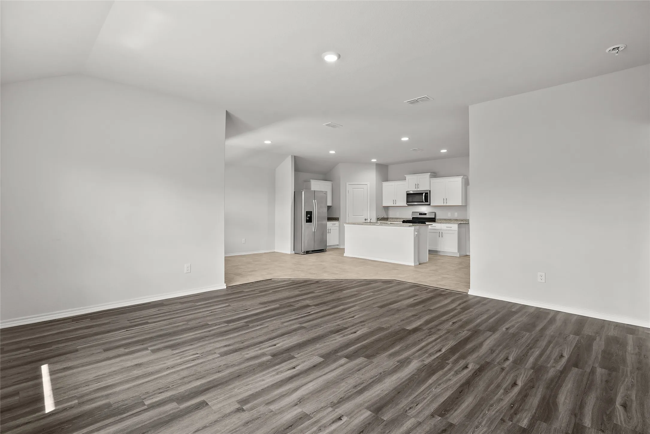 Spacious open-concept living area featuring wood-finish flooring extending into the kitchen