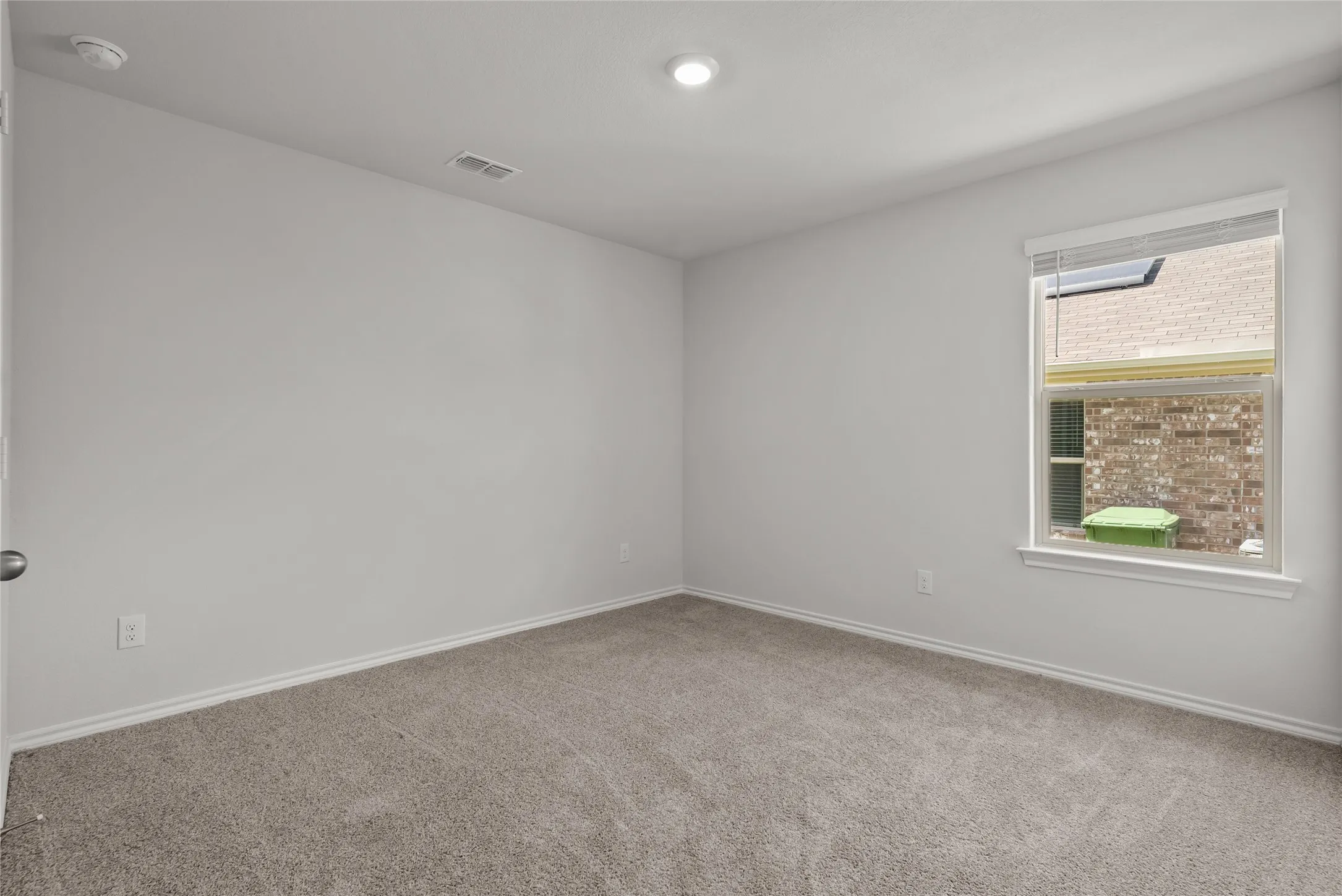 Carpeted room featuring light gray walls, a single window with blinds, and a recessed ceiling light