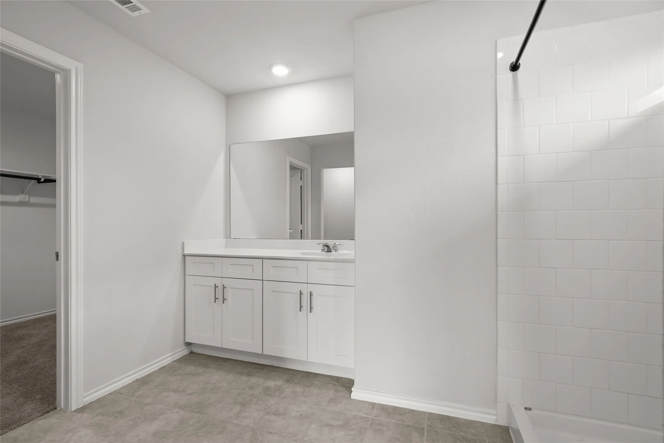 Bathroom featuring a white vanity with double-door cabinetry, a single basin sink, a large wall-mounted mirror, and overhead recessed lighting