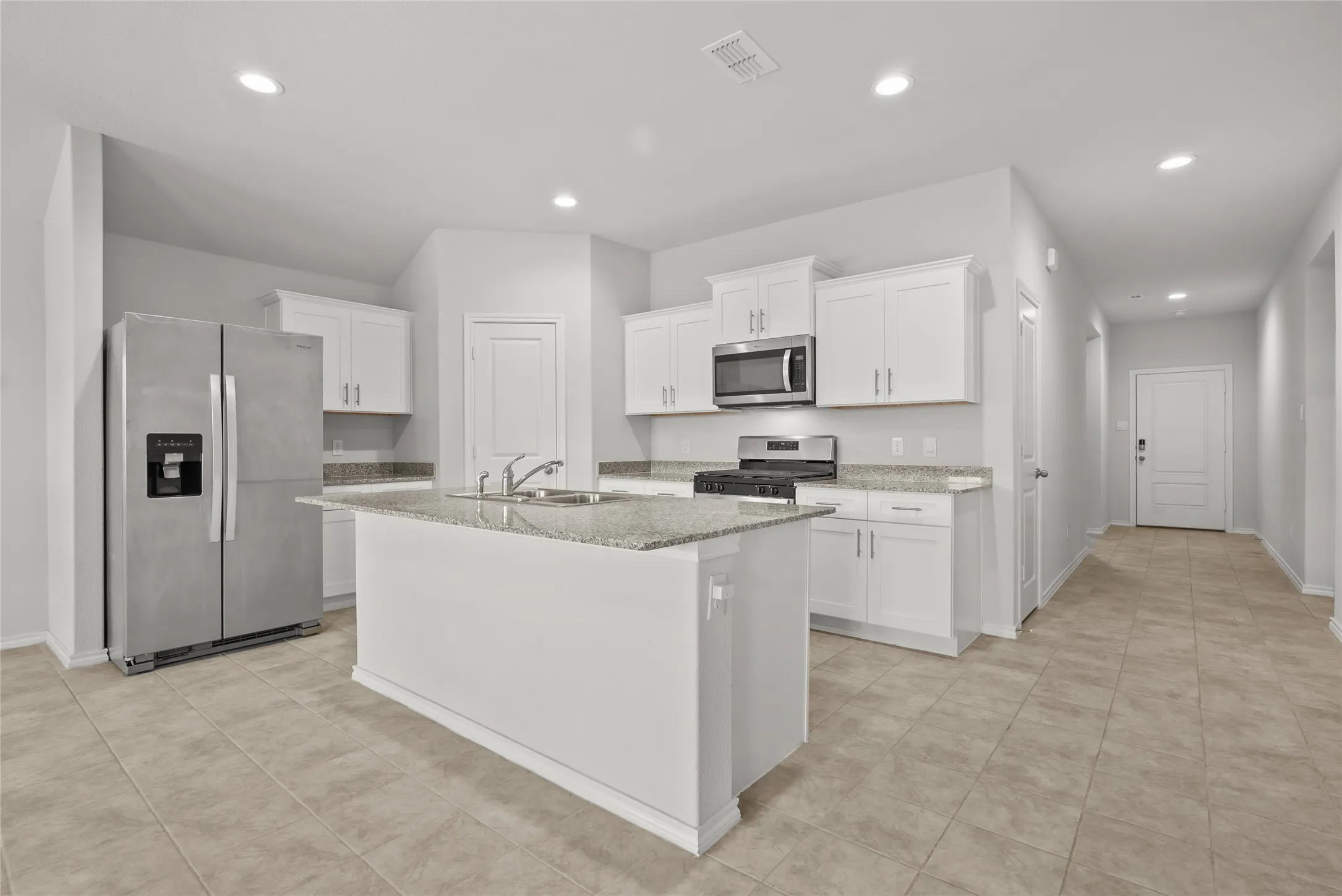 Kitchen featuring an island, white cabinetry, a stainless steel side-by-side refrigerator, a stainless steel microwave, and recessed lighting
