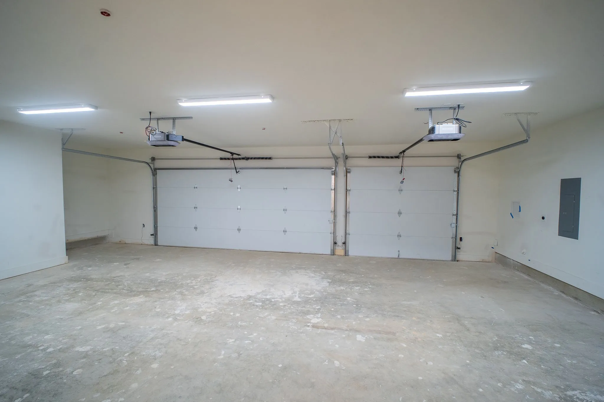 The property features an expansive garage with two overhead doors, each equipped with an automatic opener