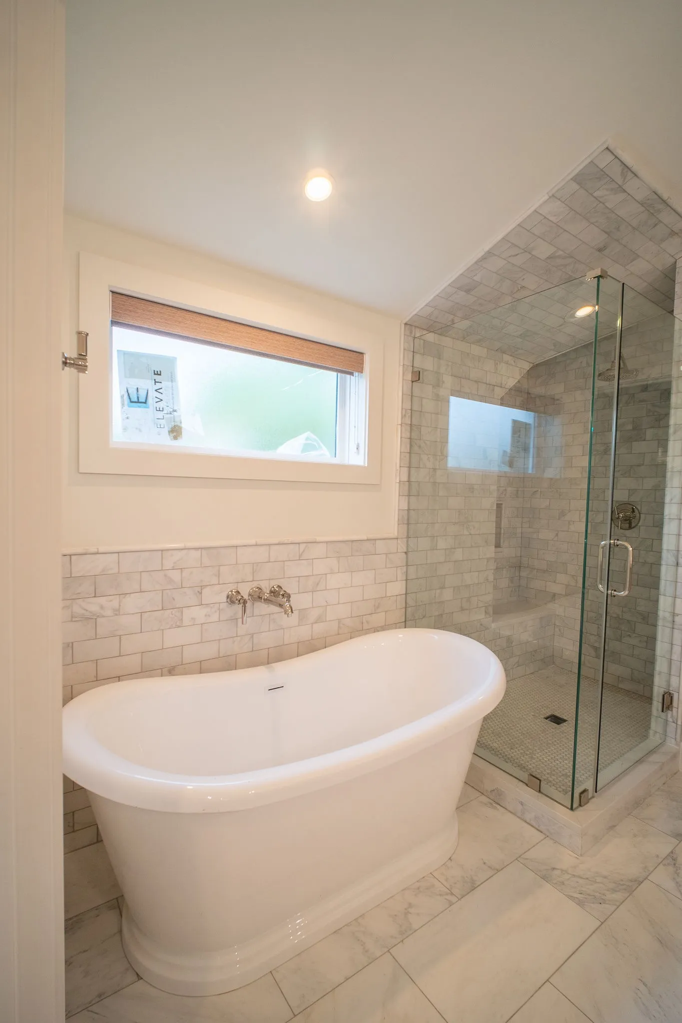 Bathroom featuring a freestanding bathtub, a glass-enclosed shower, and subway tile accents