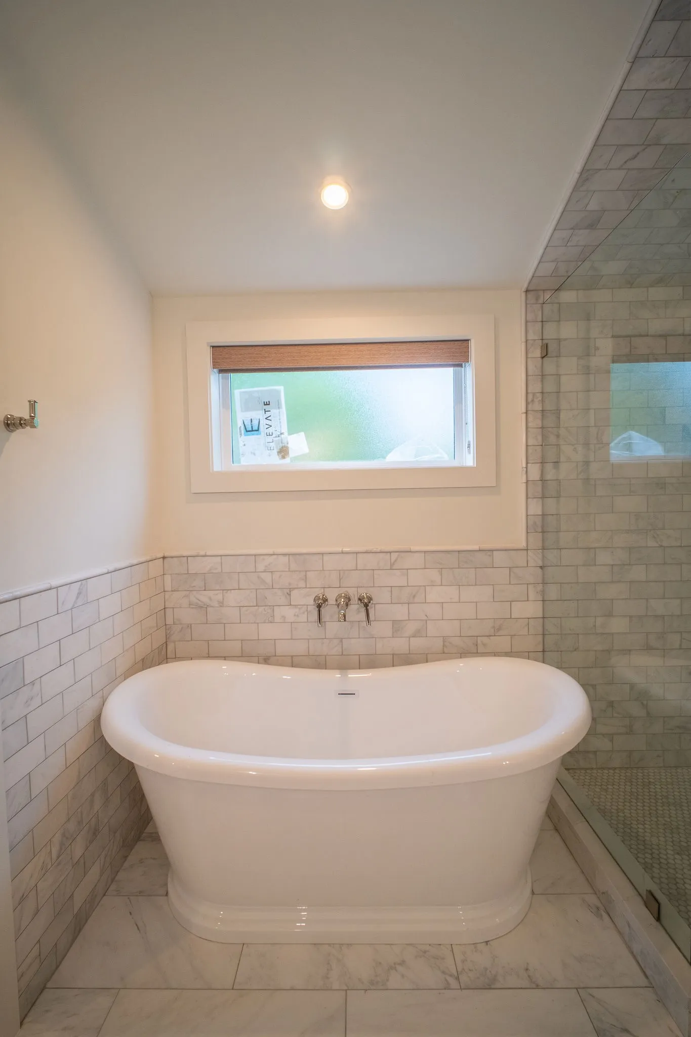 Bathroom featuring a freestanding tub, subway tile wainscoting, and large format tile flooring